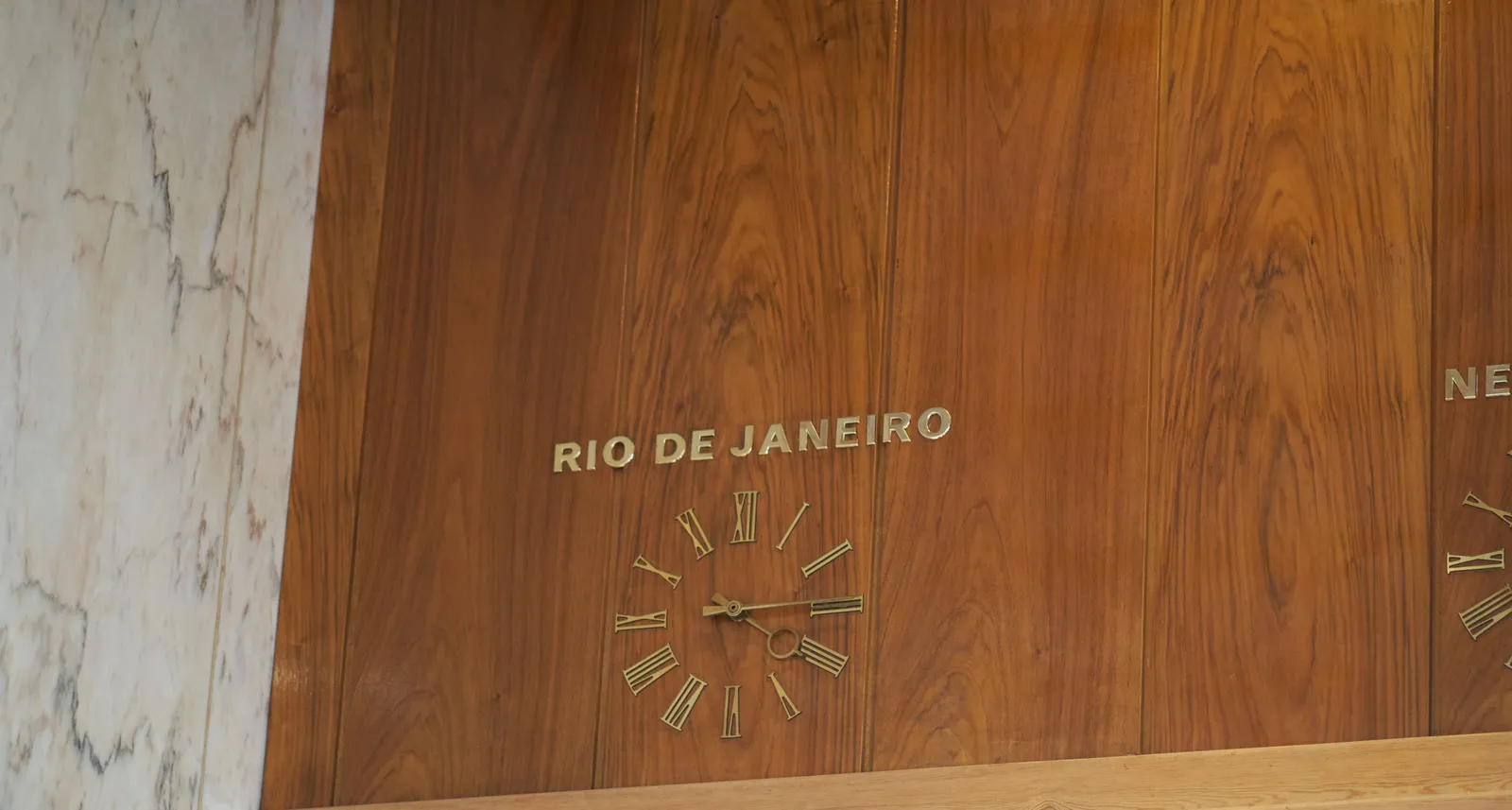 A lathed wall with a built in clock. Above the clock it says Rio de Janeiro. The clock points at 14 minutes past 4.