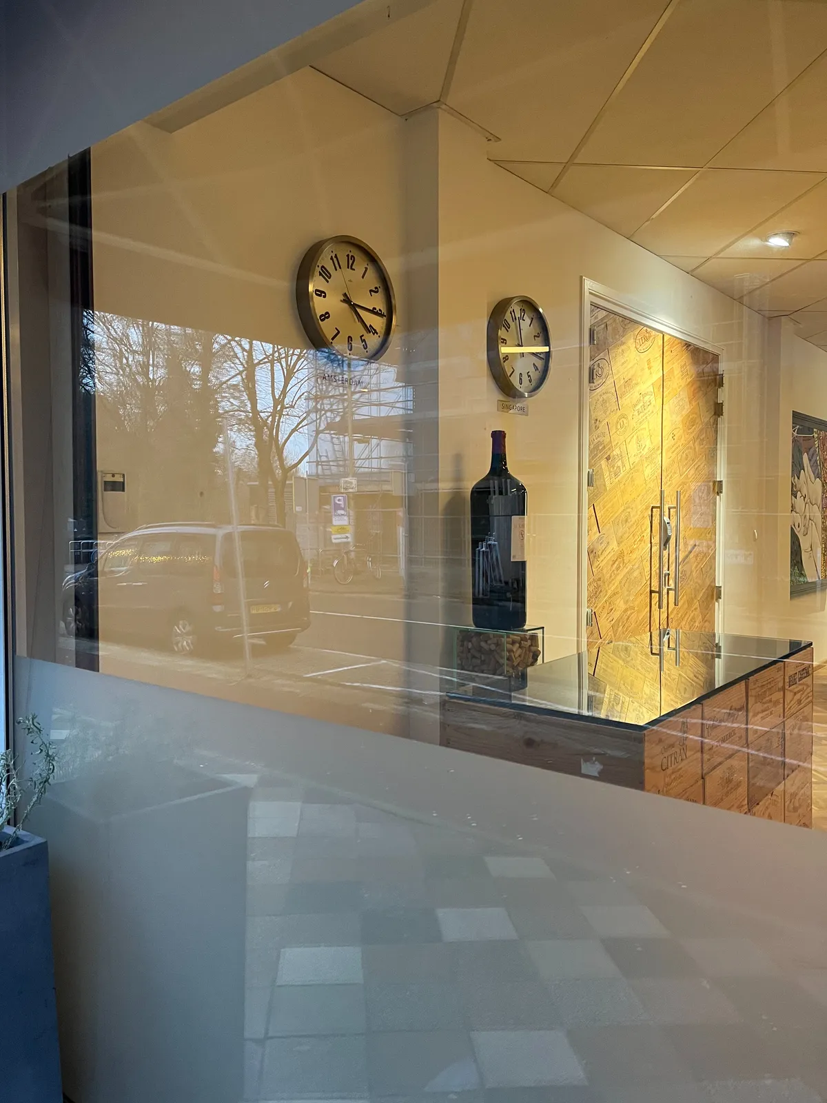 A large bottle of wine, a golden door, and two clocks. One of them points at a quarter past 4, the other at 16 minutes past 11. One of them is correct.