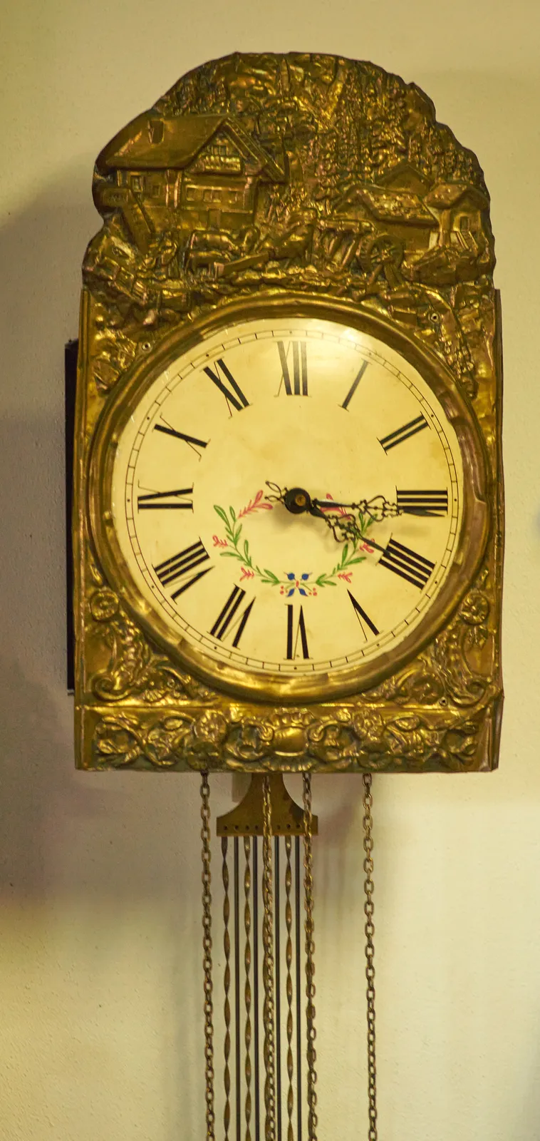 An old golden clock with latin numerals. Its arms point at sixteen past four.