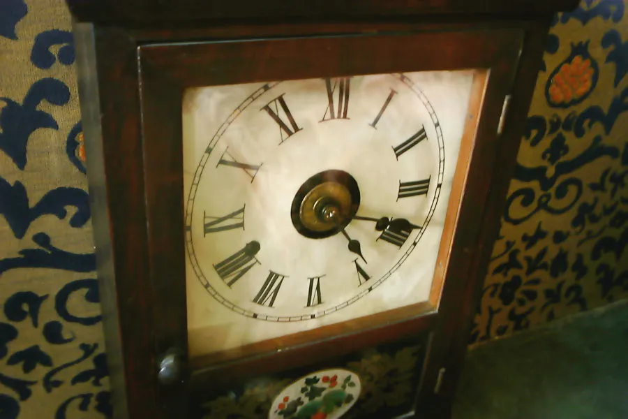 An old clock in a wooden frame points at 18 minutes past four.