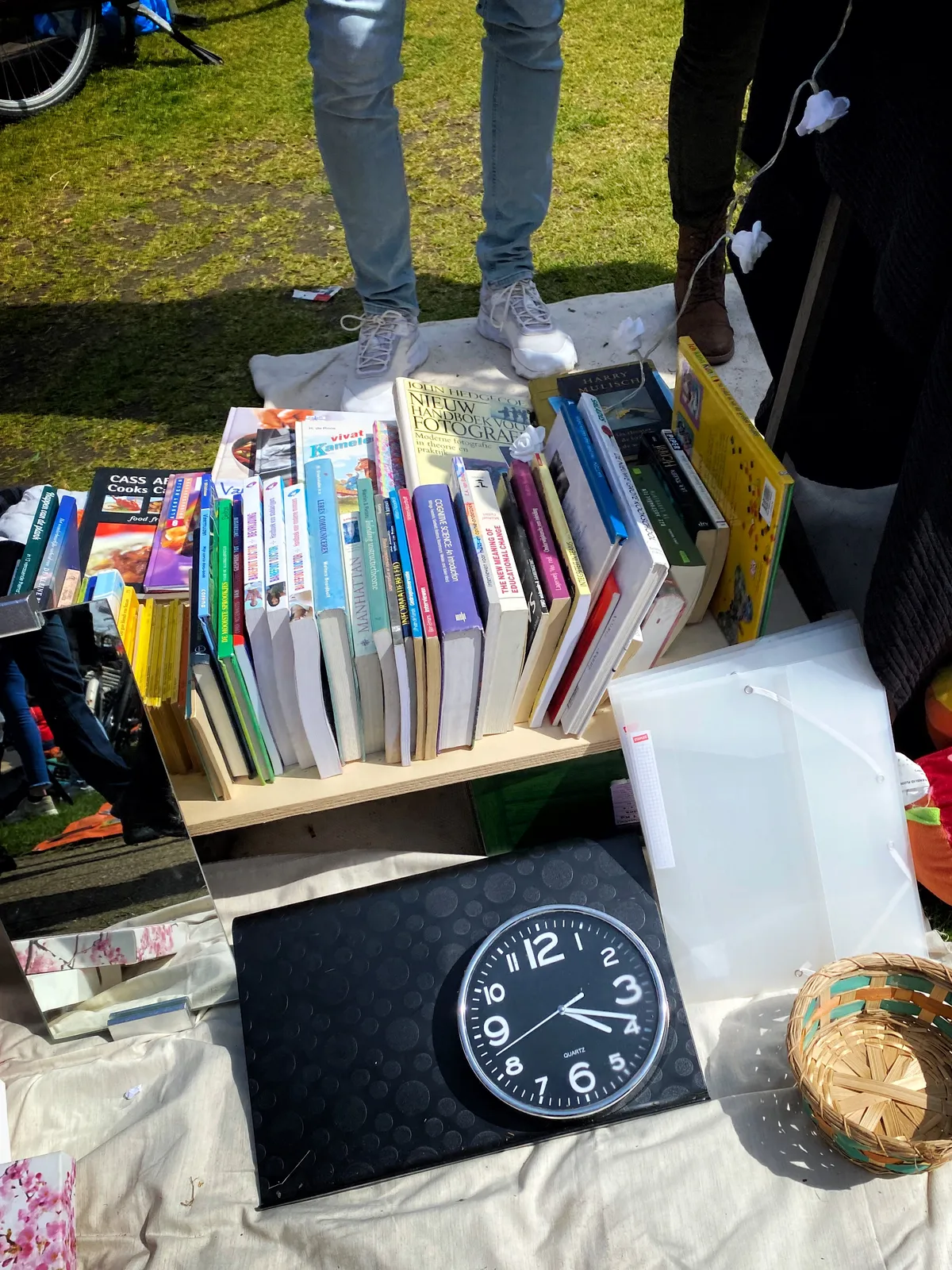 The feet on this picture are probably of the person selling mostly books at a flea market. But they’re also selling a clock, which points at 18 past 4.