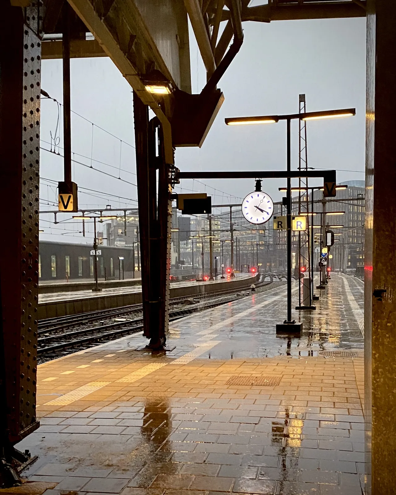 A very, very rainy train station. The clock points at 19 minutes past 4.