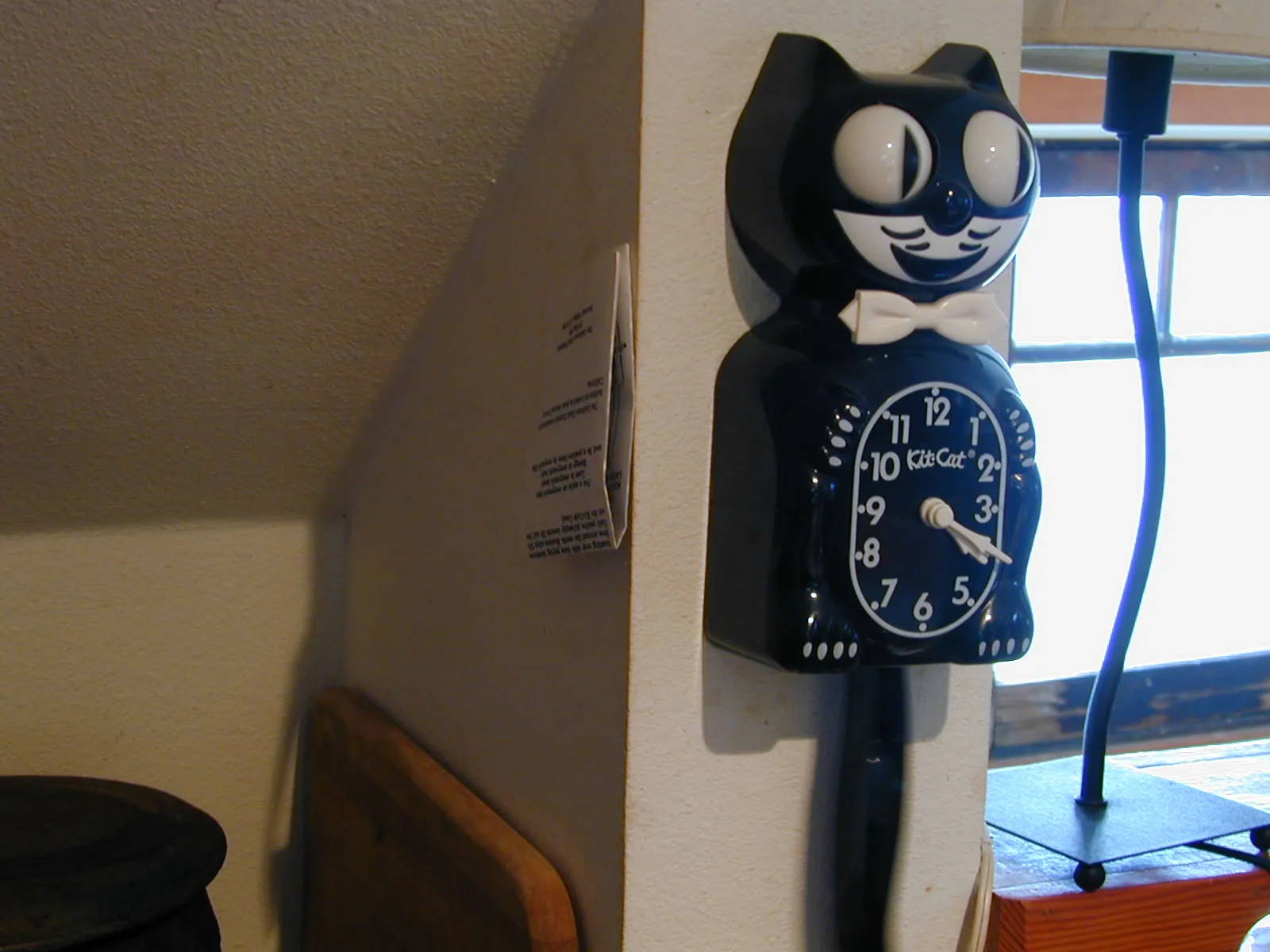 A clock in the shape of a cat says it is twenty past four.