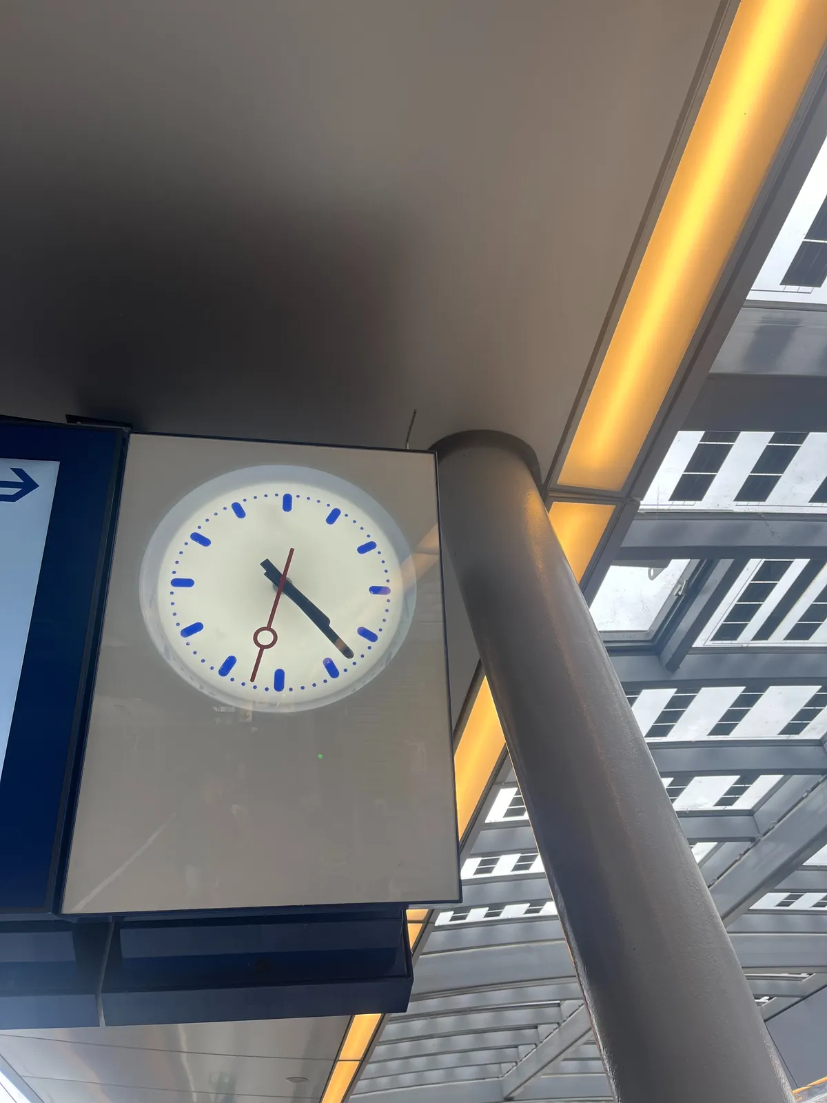 A very plastic, clean clock in a train station that points at 23 minutes past 4.