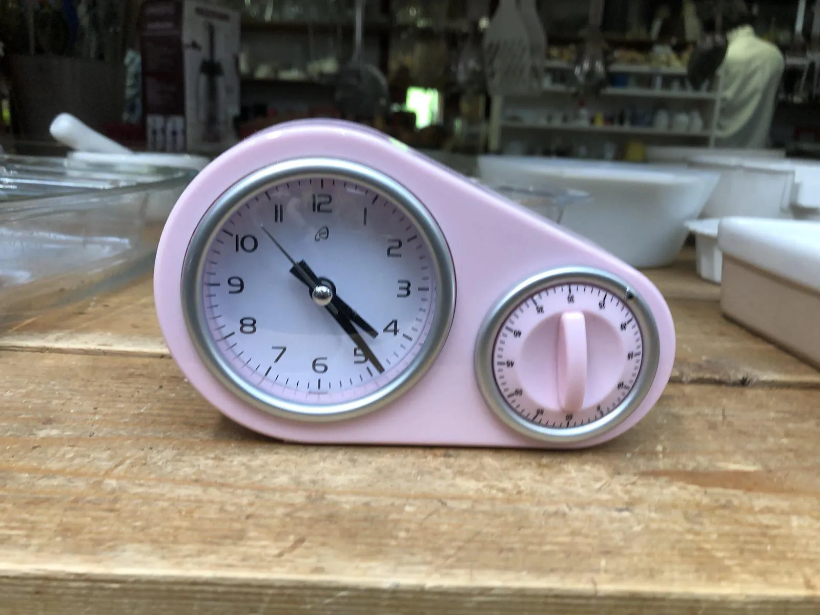 A pink time piece with both a mechanical timer and a clock. The clock points at 24 past 4.