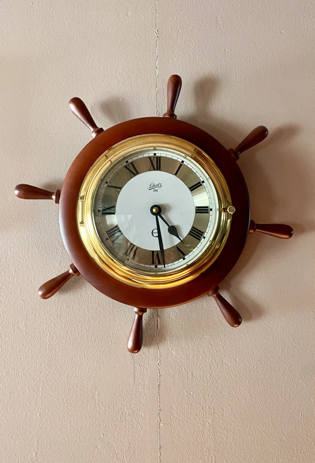 A clock built into the helm of a boat. It points at 28 minutes past 4.