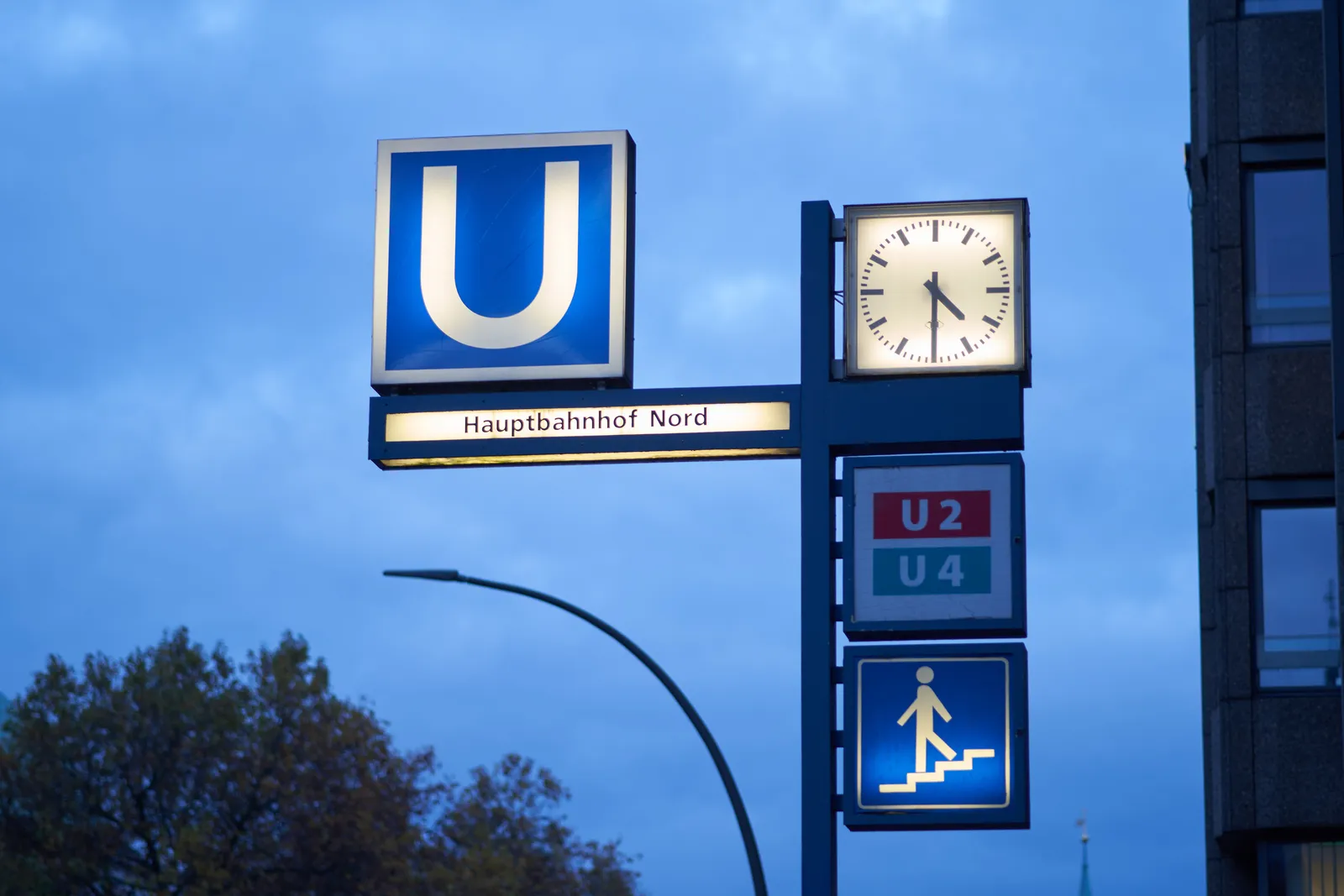 A lit sign that indicates that here you will find the stairs down to the U-bahn station Hauptbahnhof Nord. The light in the sign that shows the train numbers is broken, but you can still read that you can take U2 and U4 here. The clock shows it’s half past 5.