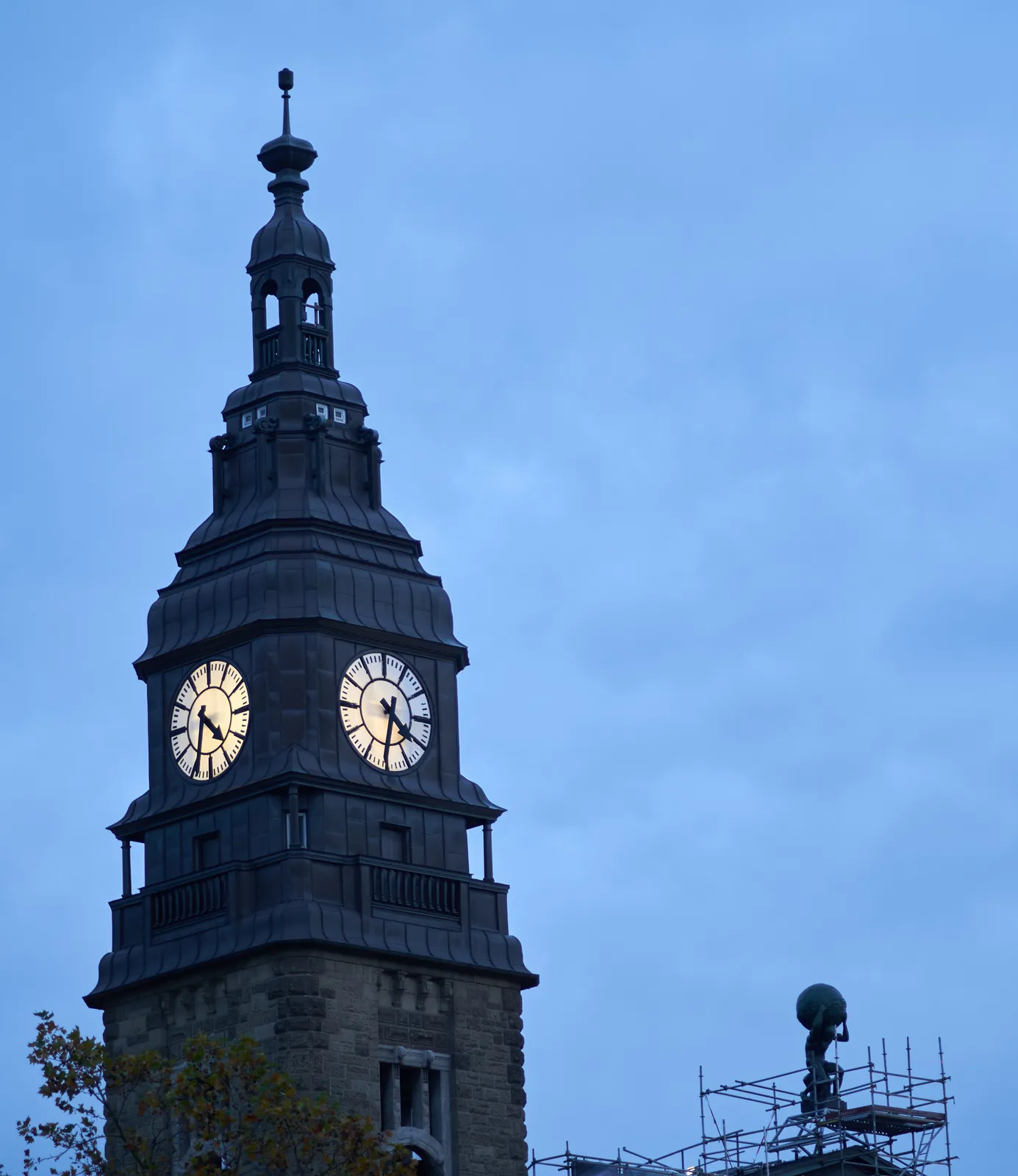 In the bottom right corner of this image you van see a statue of a kneeling Atlas, carrying the world on his shoulders. He’s surrounded by scaffolding so it looks like help is on its way. Much more prominent is a large dome with a clock on two sides. They point at different minutes, but on average they point at 28 minutes to 5.