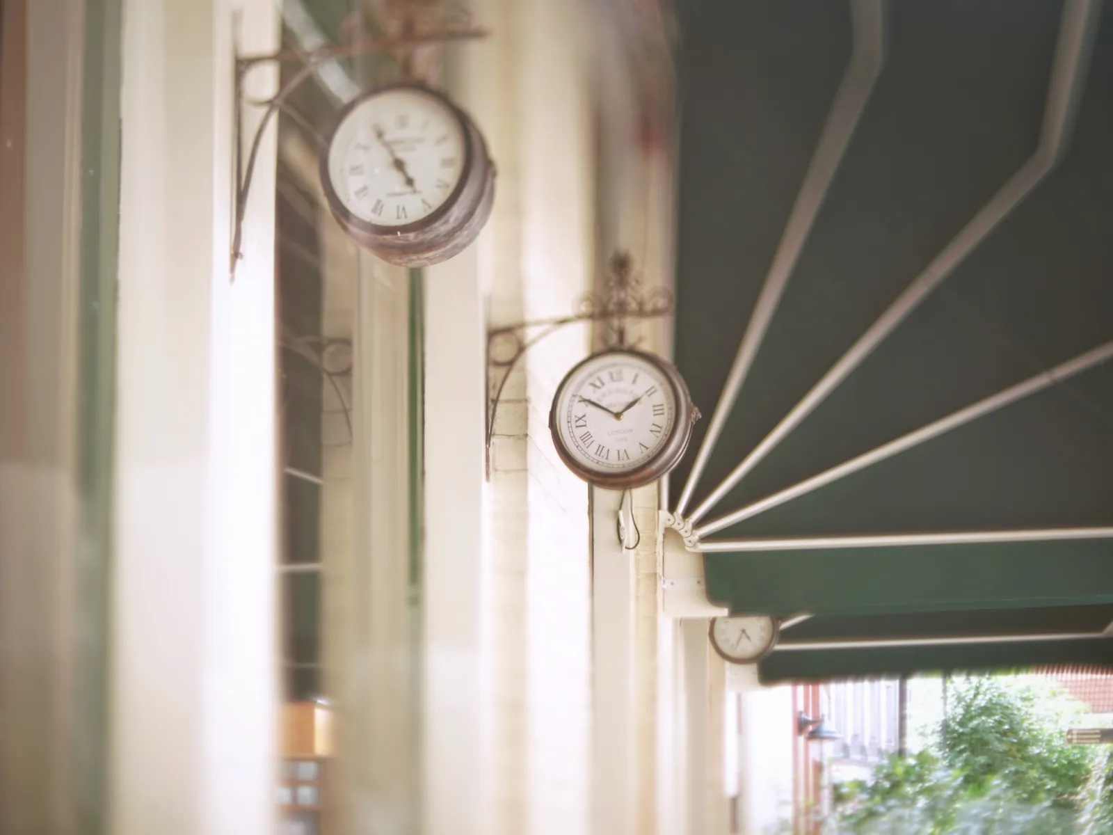 There are three clocks attached to this cafe. The one in the back, which is somewhat in focus, points at 34 past 4.