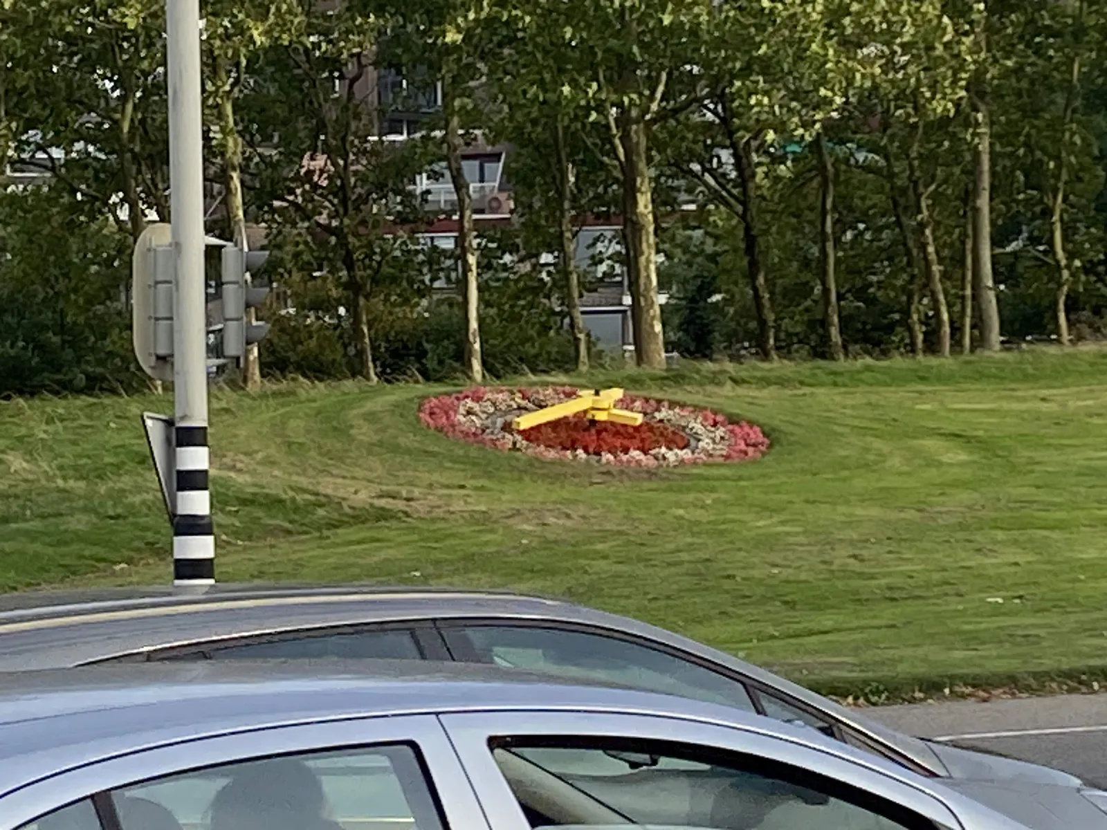 On a grassy little hill there’s a circle of flowers which is a clock. It’s very hard to see what time it is, but it could very well be 36 minutes past four.
