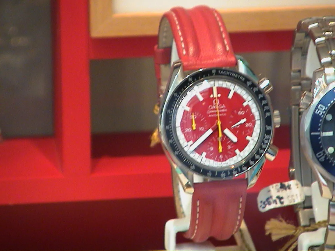 A red watch in a shop window points at thirty nine past four.