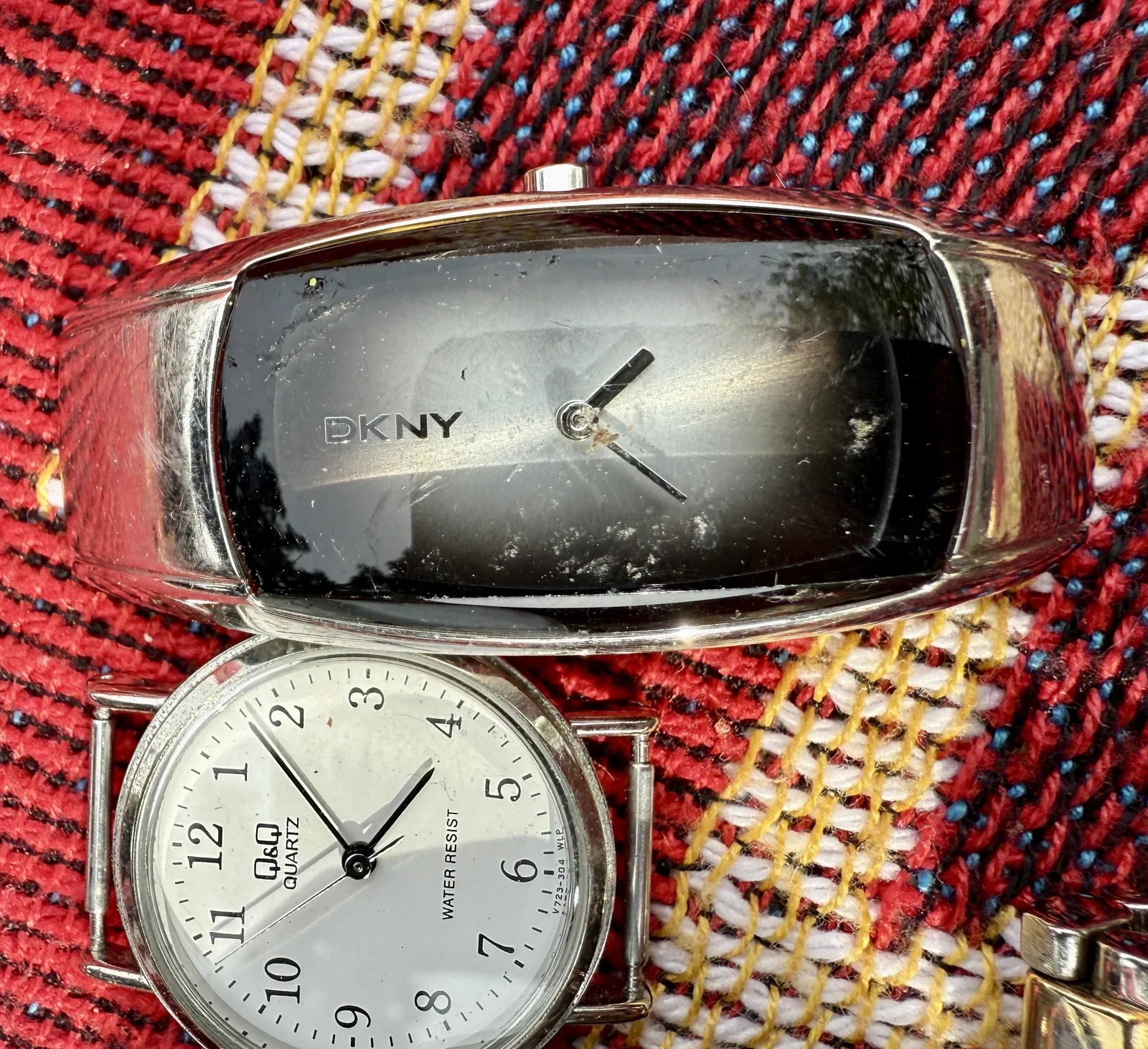 Two watches on a rug. One of them clearly points at 8 minutes past four. The other one either points at approximately 24 minutes past two, or at approximately 39 minutes past four, depending on what you think the orientation of the watch should be.