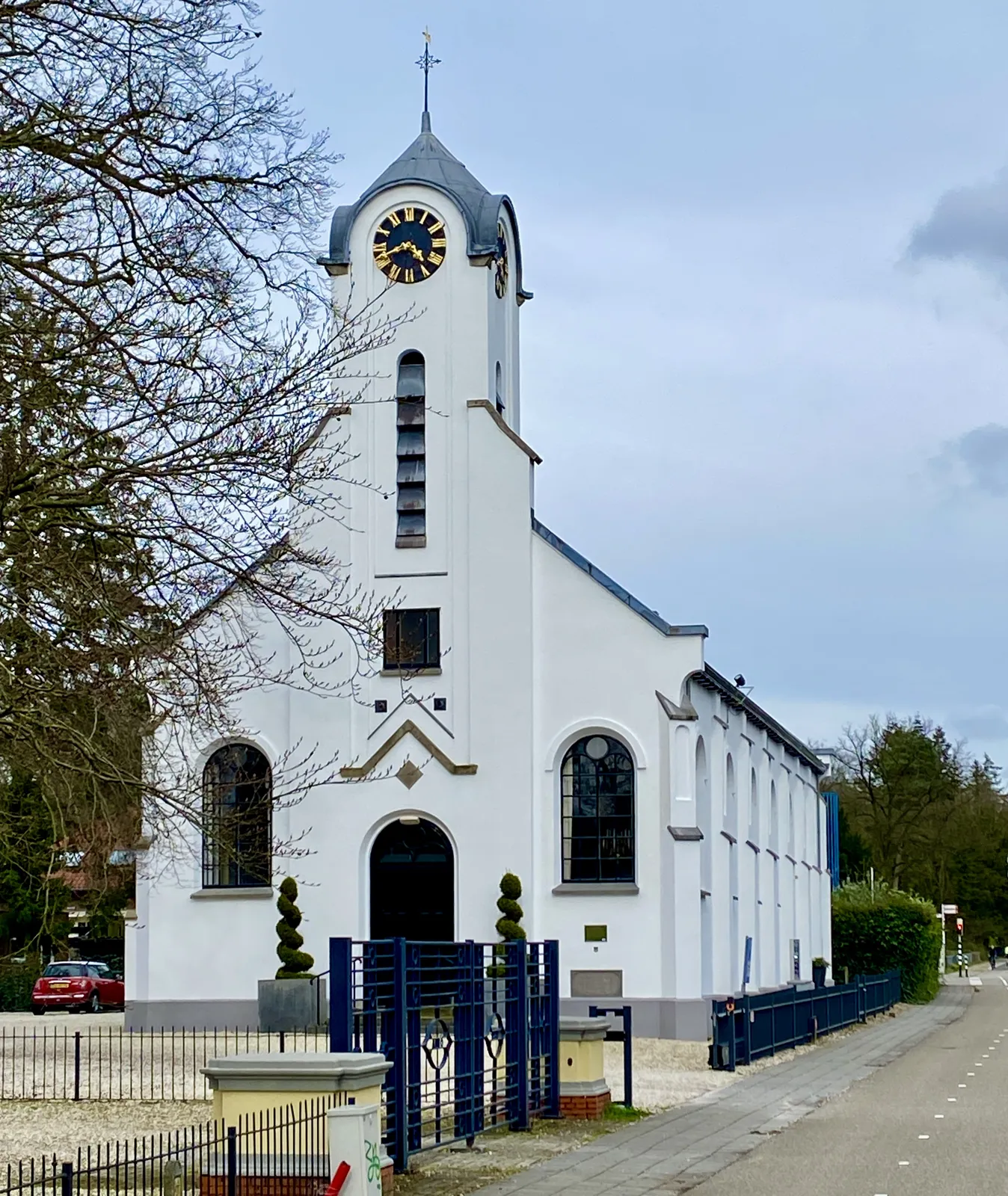 A white church with a clock on its tower. It points at 18 minutes to 5.