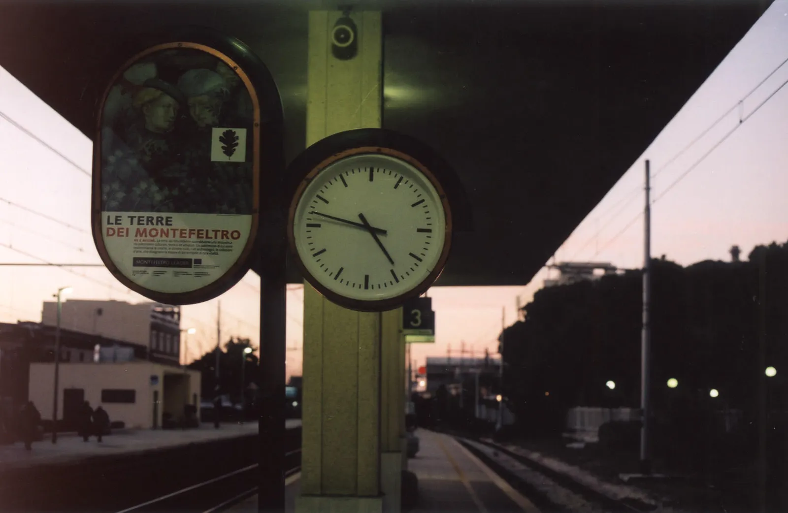 This clock on a train station points at thirteen minutes to five.