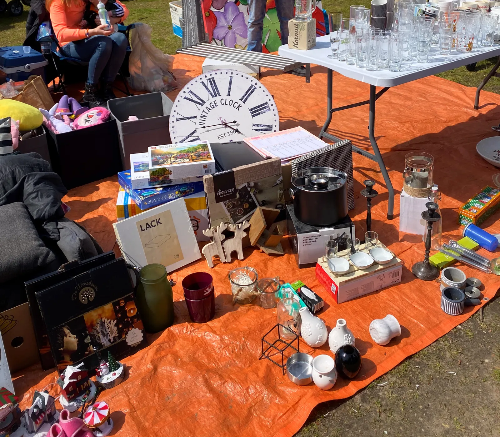 Lots and lots of stuff for sale on this flea market. A pretty large clock is among this stuff. It points at 13 minutes to 5.