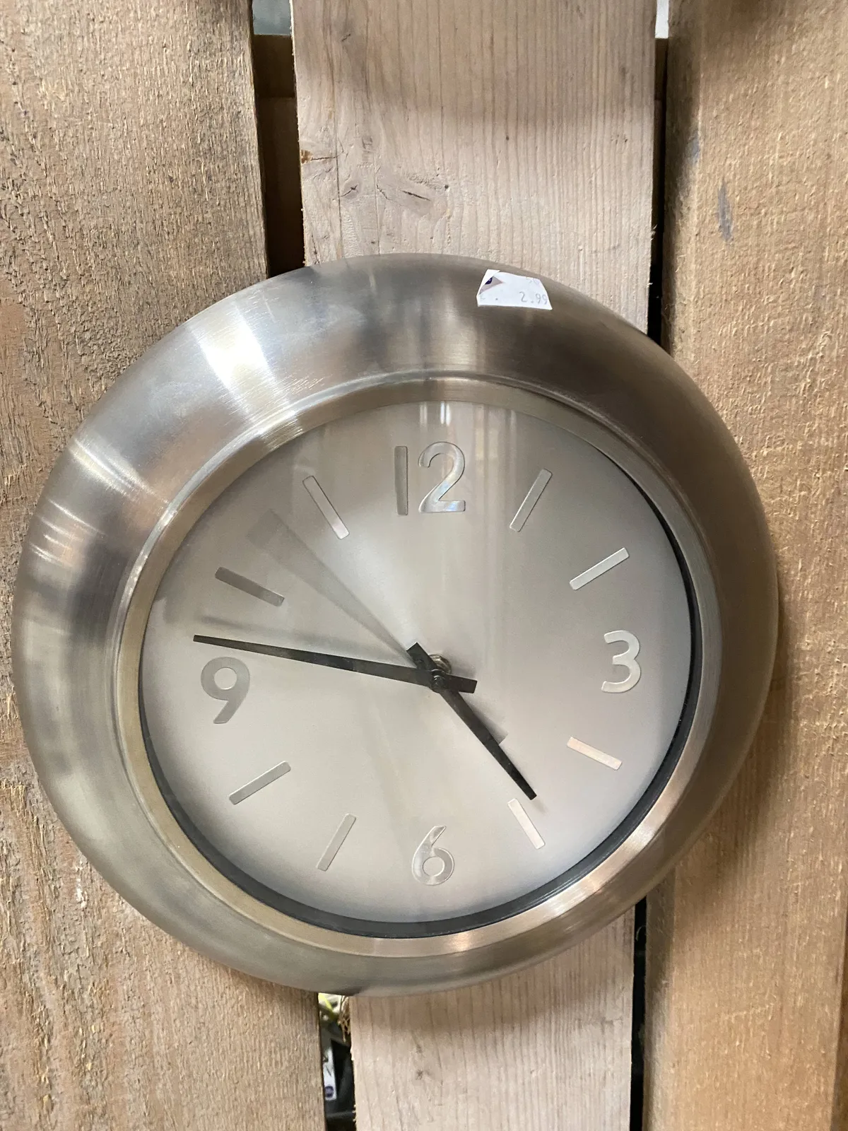 A simple metal clock points at 13 minutes to 5.