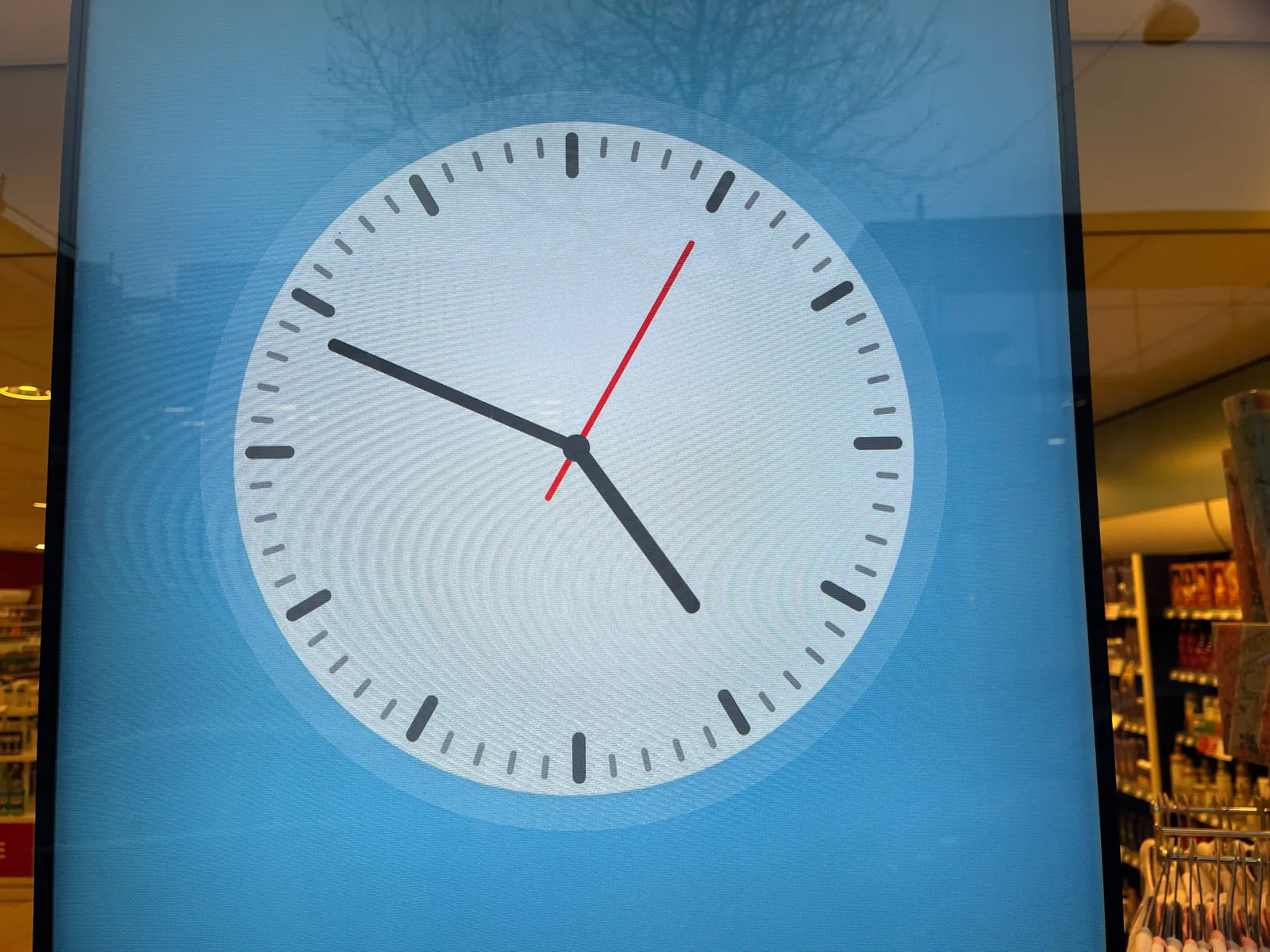 A clock on a digital display points its hands at eleven minutes to five.
