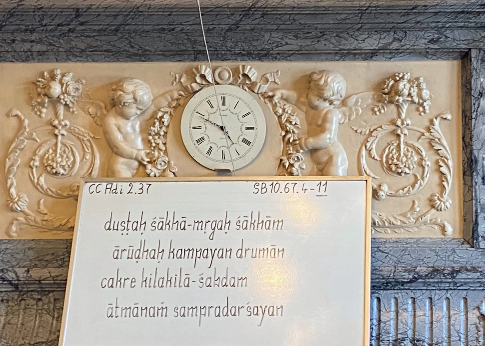 A relief with some small angels. They hold a clock which points at 11 minutes to 5.