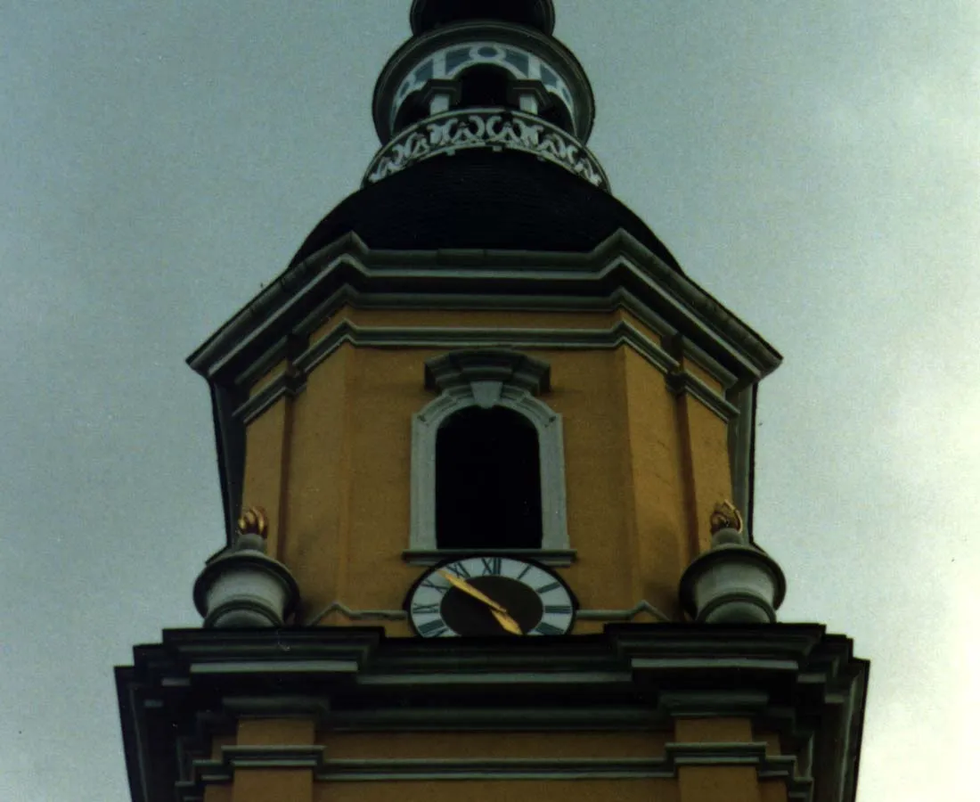 A clock on a yellow church says it is eight minutes to five.