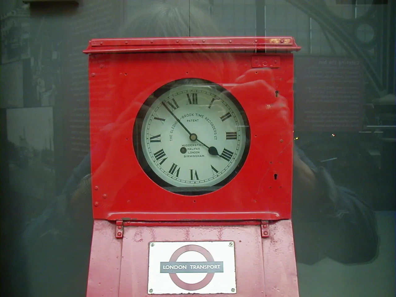 A clock in a metal London Transport case points at seven minutes to five.