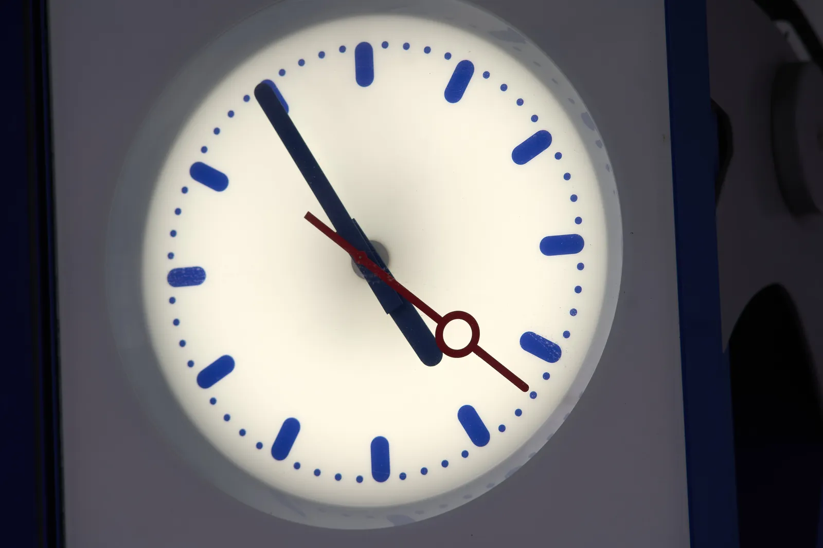 A frame filling station clock which points at 5 minutes to 5.