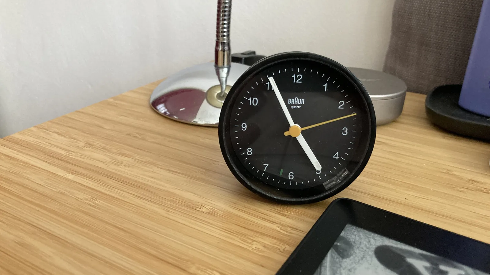 A small black Braun clock that points at 5 to 5.