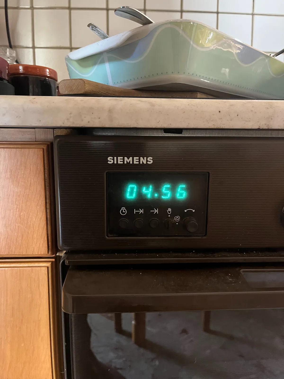 An oven tray is standing above a Siemens oven. On this oven there’s a digital clock which shows the time as 04.56
