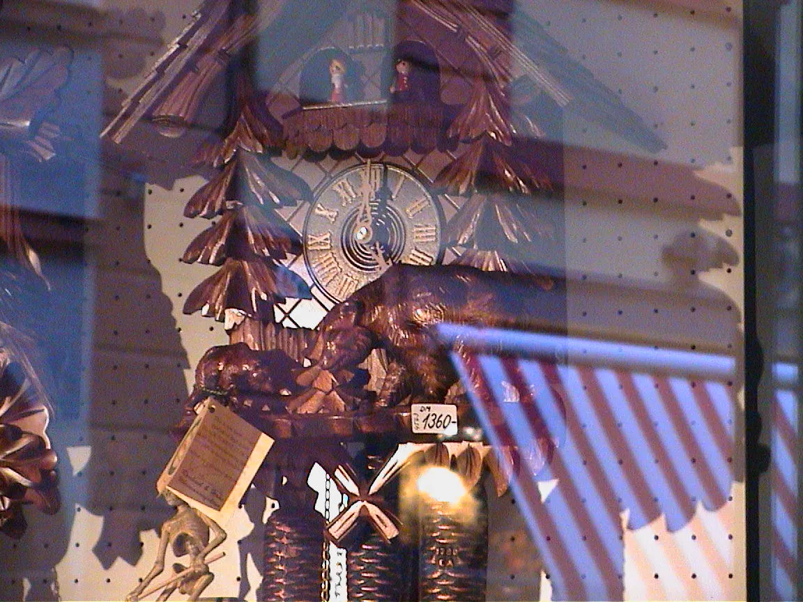 A cuckoo clock in a shop window points at five o’clock.