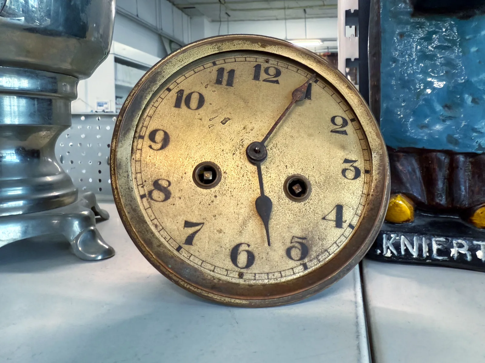 An old corroded clock face. It points at 4 minutes past five.
