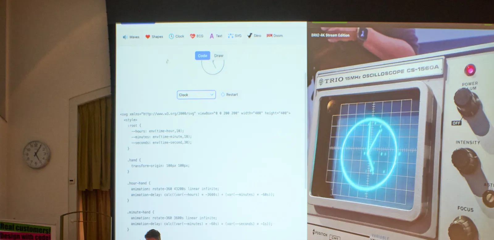 There’s a clock projected on a screen. This clock itself is projected on an old osciloscope. The code that does this is projected on the screen, next to it. There’s also a simple wall, next to the large screen. And then there’s also the wrist watch of the presenter, also projected on the large screen. All clocks point at five minutes past five.   