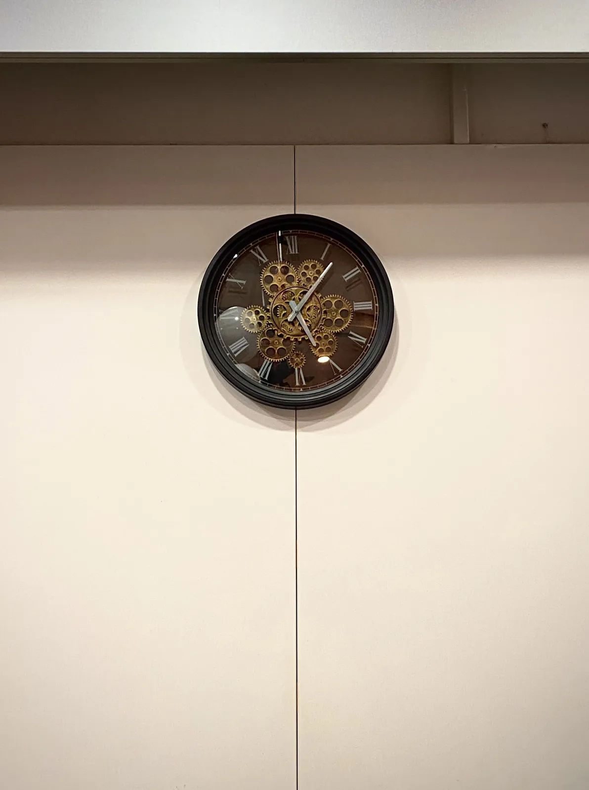 A wall clock that seems to show its inner mechanics. It points at 7 past 5.
