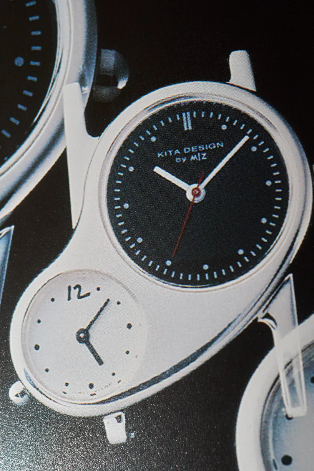 An oddly shaped wrist watch with two faces. The smaller face points at 8 minutes past five. The large one points at eight minutes past ten.