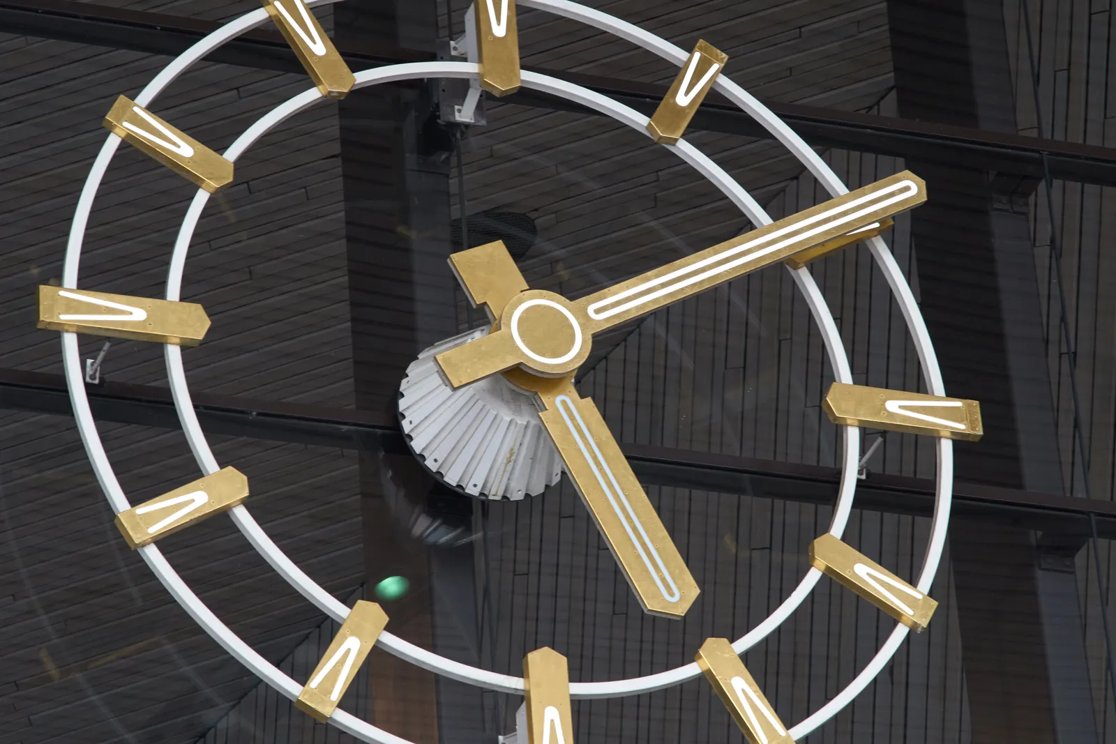 An enormous clock on a glass facade. It points at 10 past 5.
