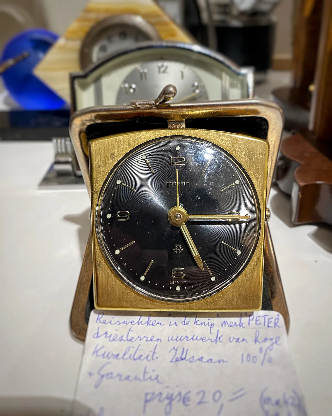 An old foldable travel clock. It points at a quarter past 5.