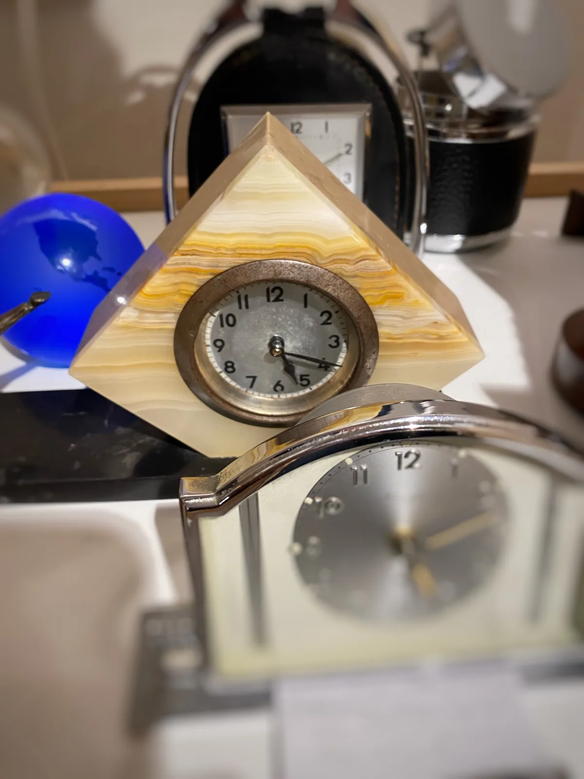 Three different travel clock behind each other. Only one of them is clearly in focus. It points at 19 past 5.