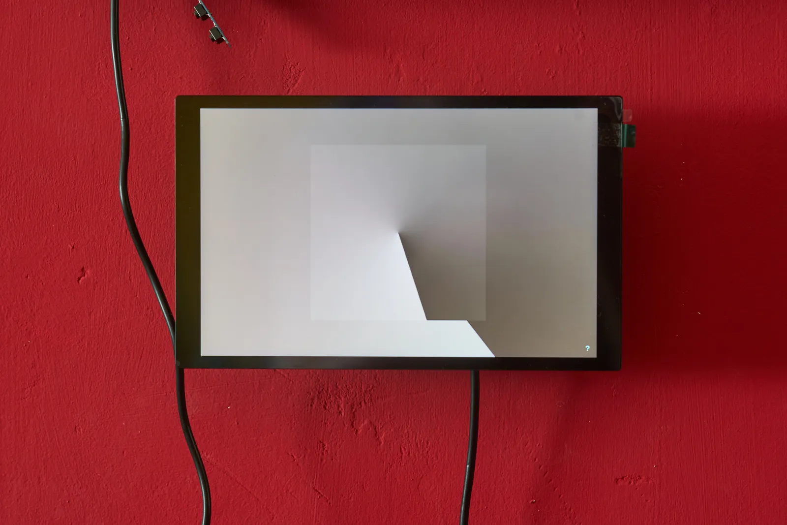 A digital screen on a red wall, showing an arty clock, made from two gradients. The gradients go from dark gray to light gray. Once you get it, you can see that it points at 24 minutes past five