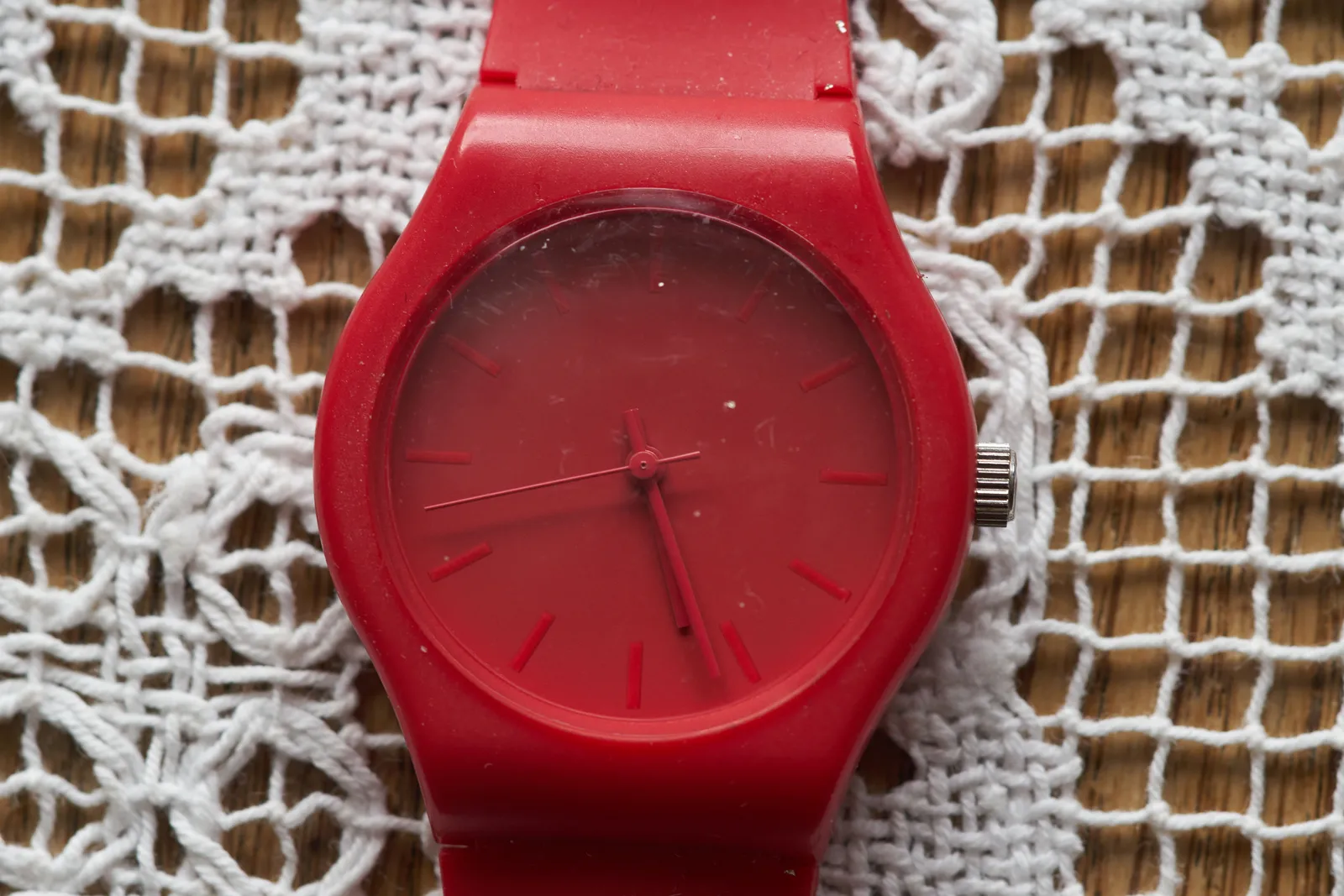 A completely red watch, red straps, red face, red hands, all red, points at 26 past 5.