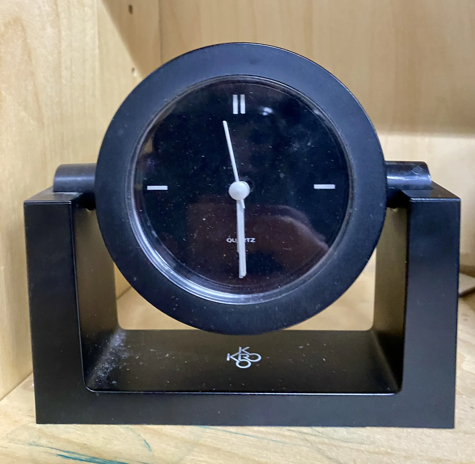 A black, modern table clock. It points at 29 minutes past 5.