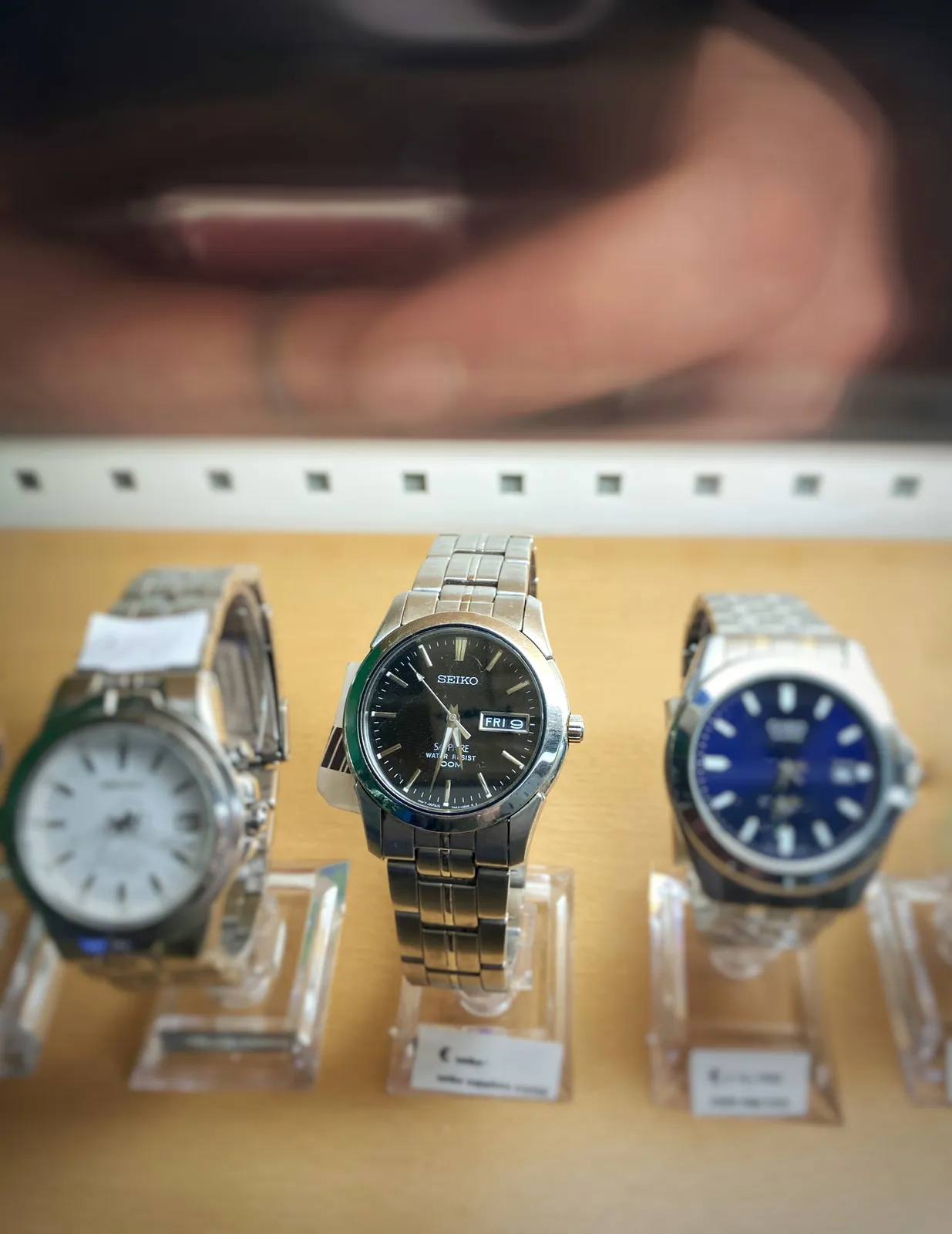 Three watches, but only the middle one is in focus. It’s a Seiko and it points at 28 minutes to 6.