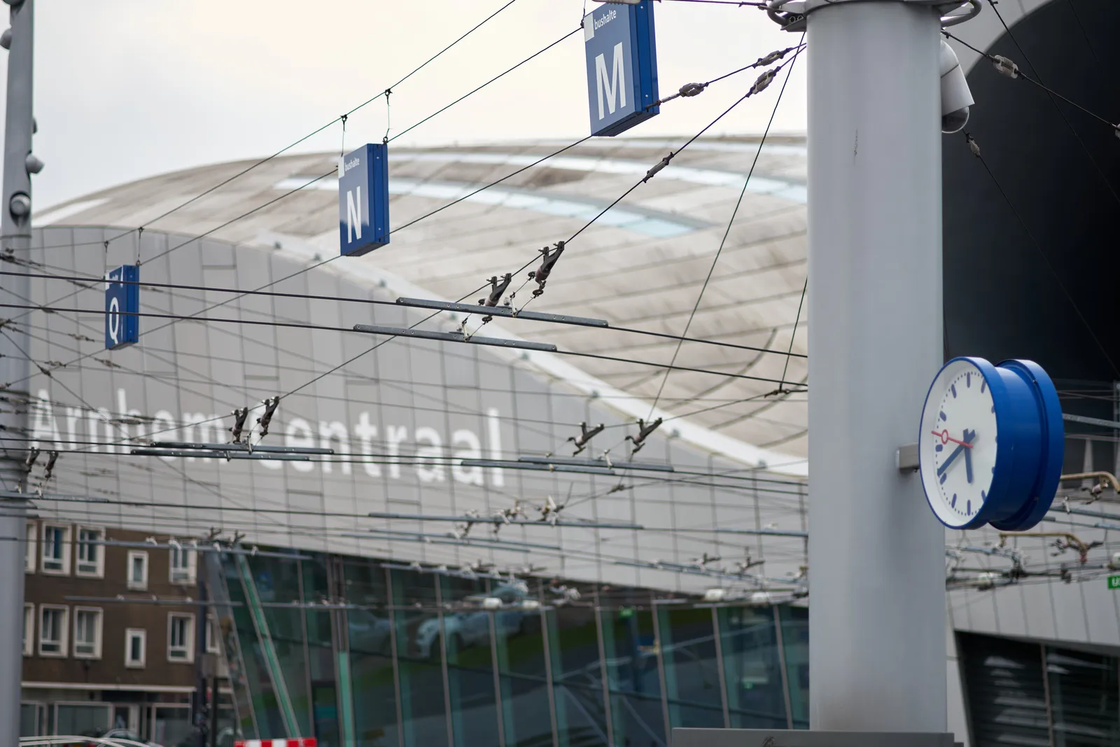 Many wires on the square in front of Arnhem Central station. There’s a clock attached to a pole that points at 41 minutes past five.
