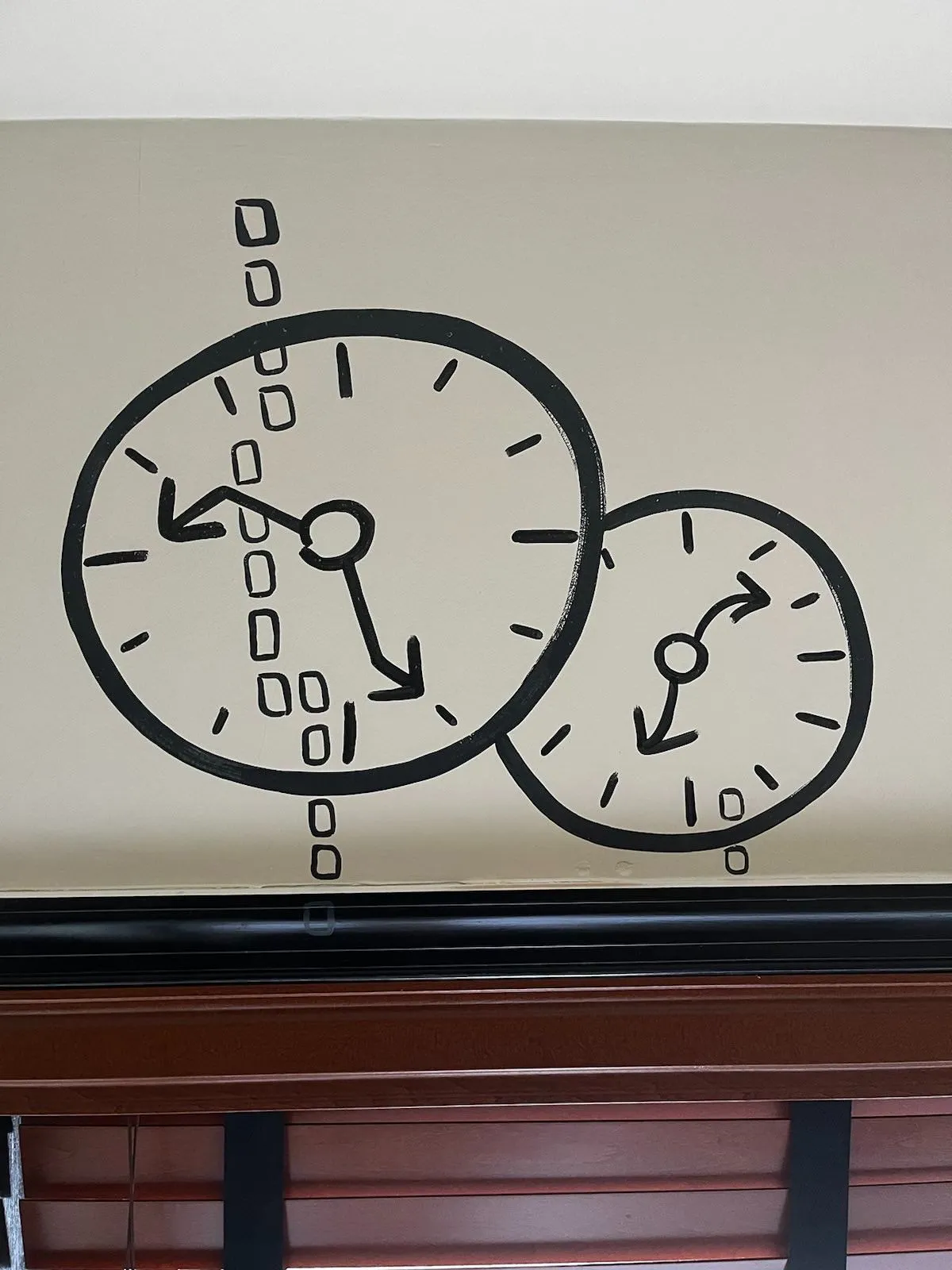 There are two hand drawn clocks on this wall. All the hands of both clocks are wavy, or skewed, so assumptions have to be made. One of the clocks may very well point at approximately 14 minutes to six, and the other might point at approximately 9 minutes past 7. One of them is right.