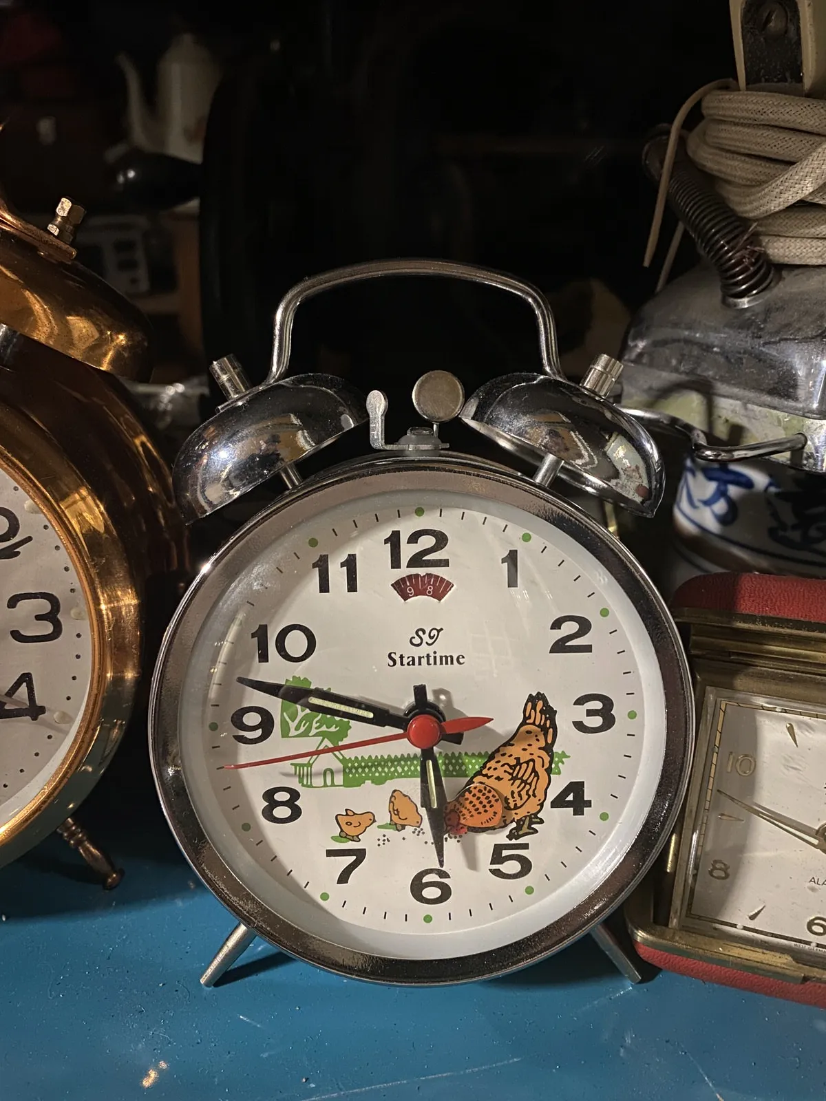 On this old alarm clock, with bells on top and chicken printed on its face, it is 47 past five.