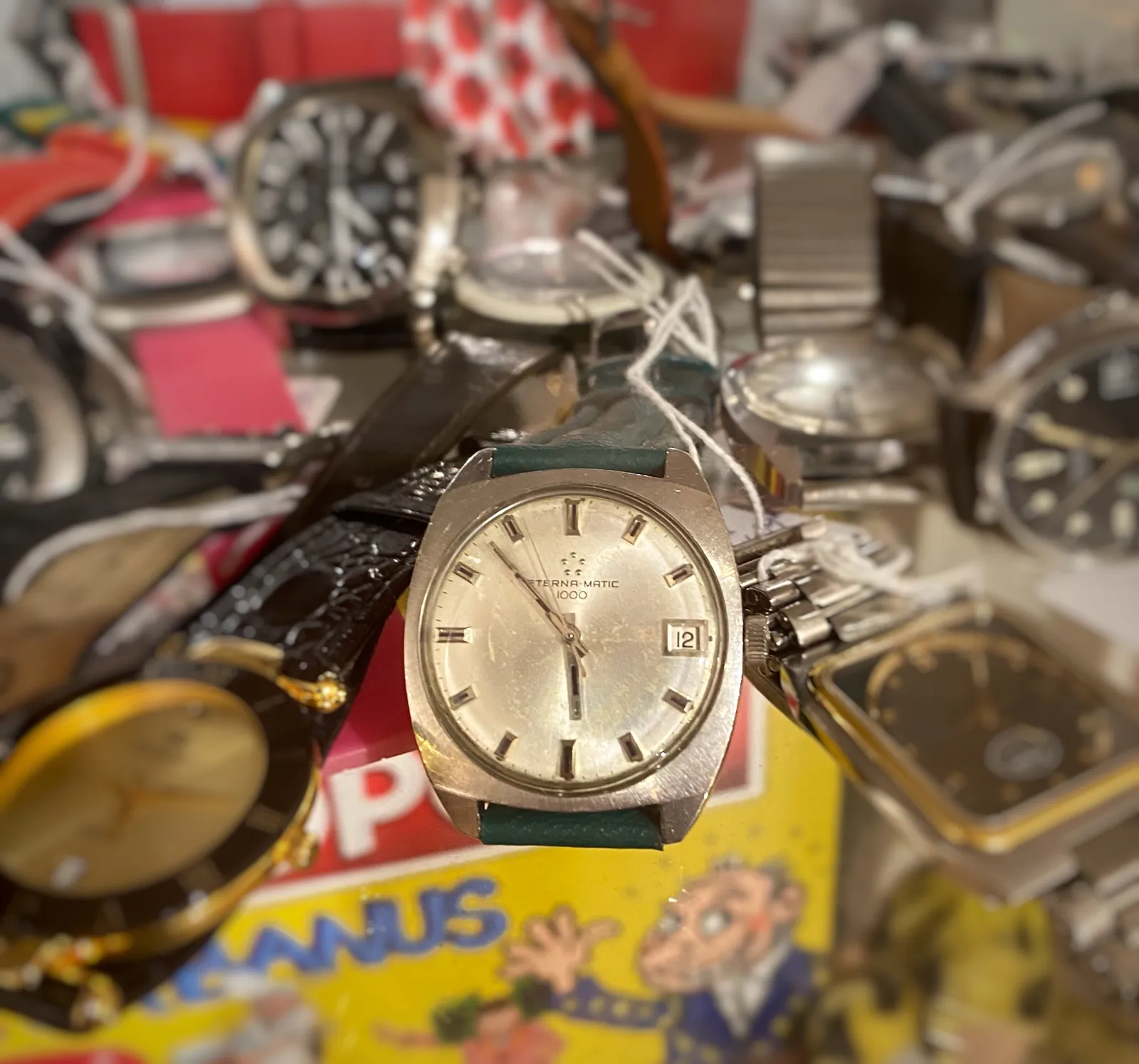 Quite a few old wrist watches for sale. Just one of them is clearly in focus. It points at 8 minutes to 6.