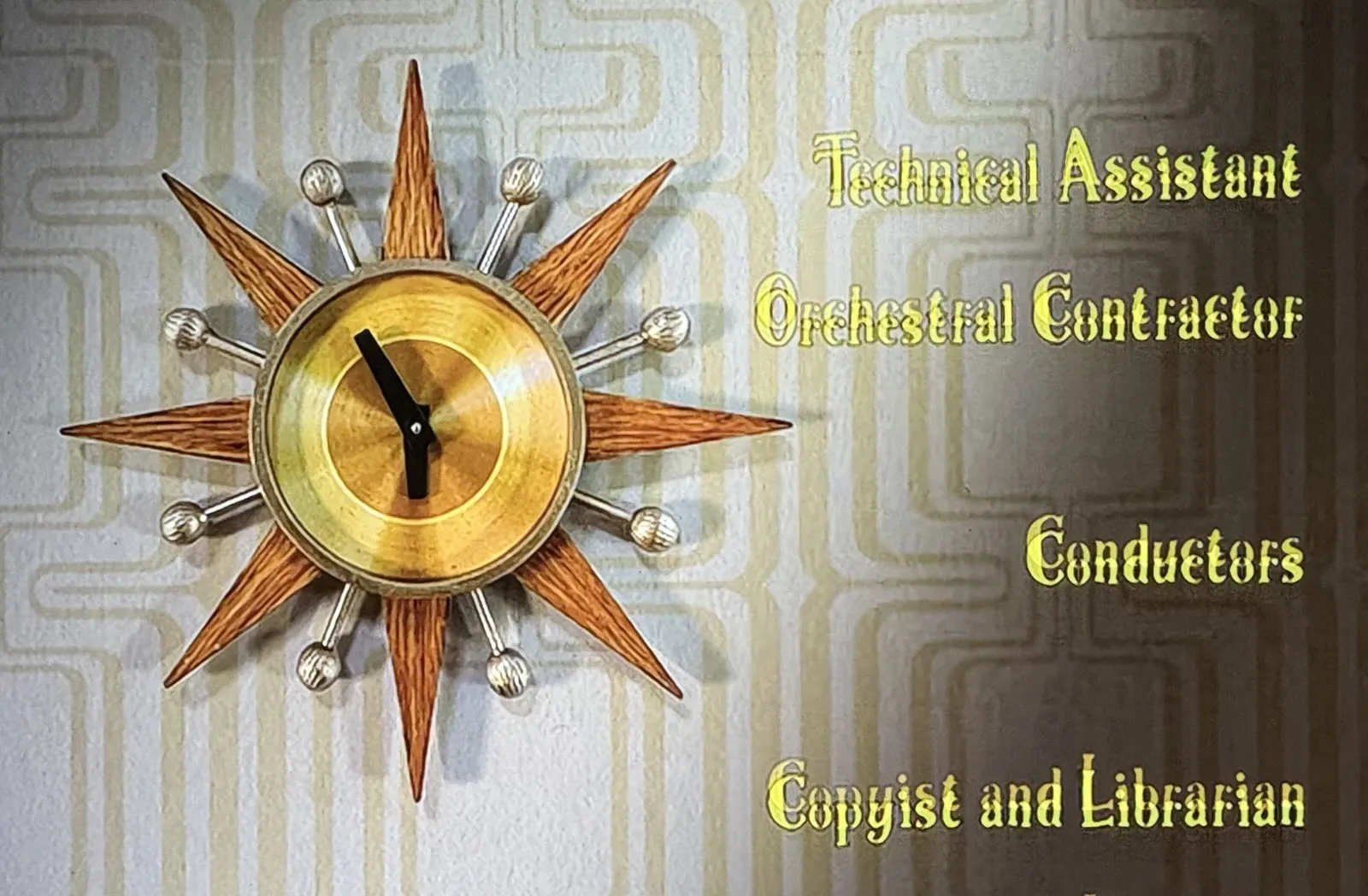 A picture taken from the credits of a movie. On the right, there’s a list of specialists: Technical Assistant, Orchestral Contractor, Conductors and Copyist and Librarian. On the left there’s an expressive clock with points and balls, which points at 6 minutes to six.