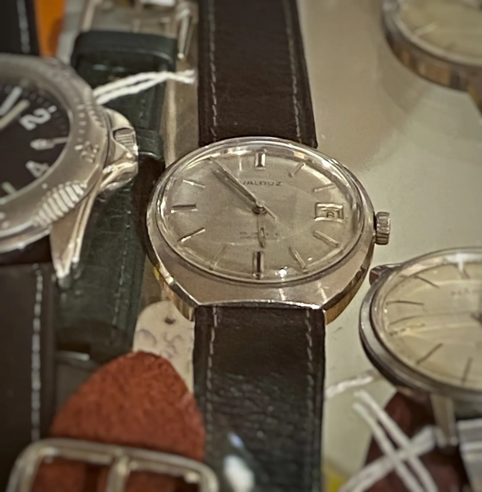 A few old wrist watches, but only on one of them the time can be seen, the rest of them are too much outside of the picture frame. It points at 5 minutes to 6. 