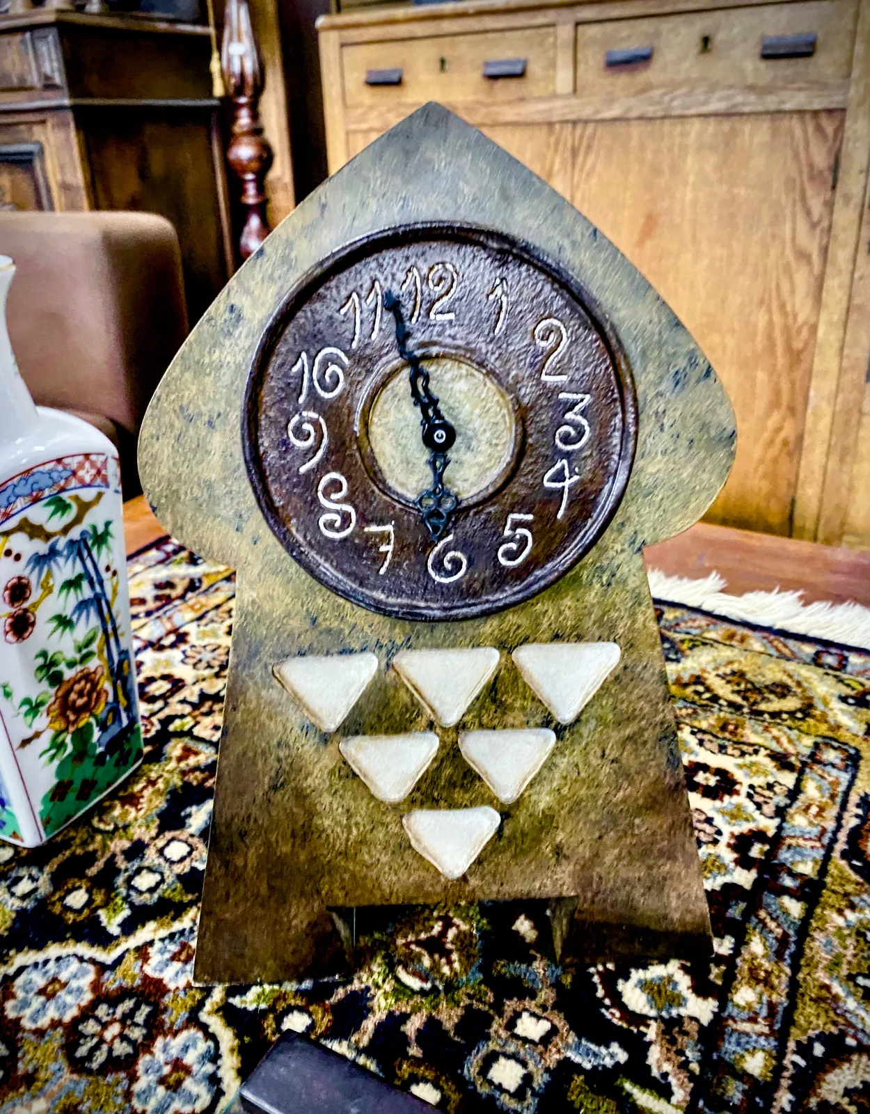 A strange, somewhat psychedelic brown ceramic clock. A bit mushroom shaped with six downward pointing white triangles on it. It points at 3 minutes to 6.