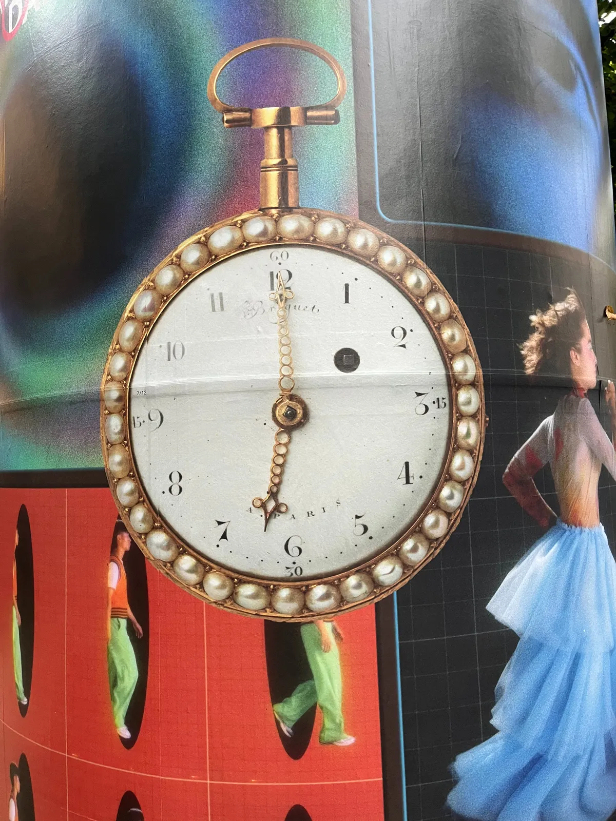 A picture of a golden clock, ornamented with pearls, which is part of a colourful collage. The clock is off. The minute hand points straight up, yet the hour hand points somewhere between 6 and 7. But a bit more towards 6, so let’s assume that it points at 6 o’clock.