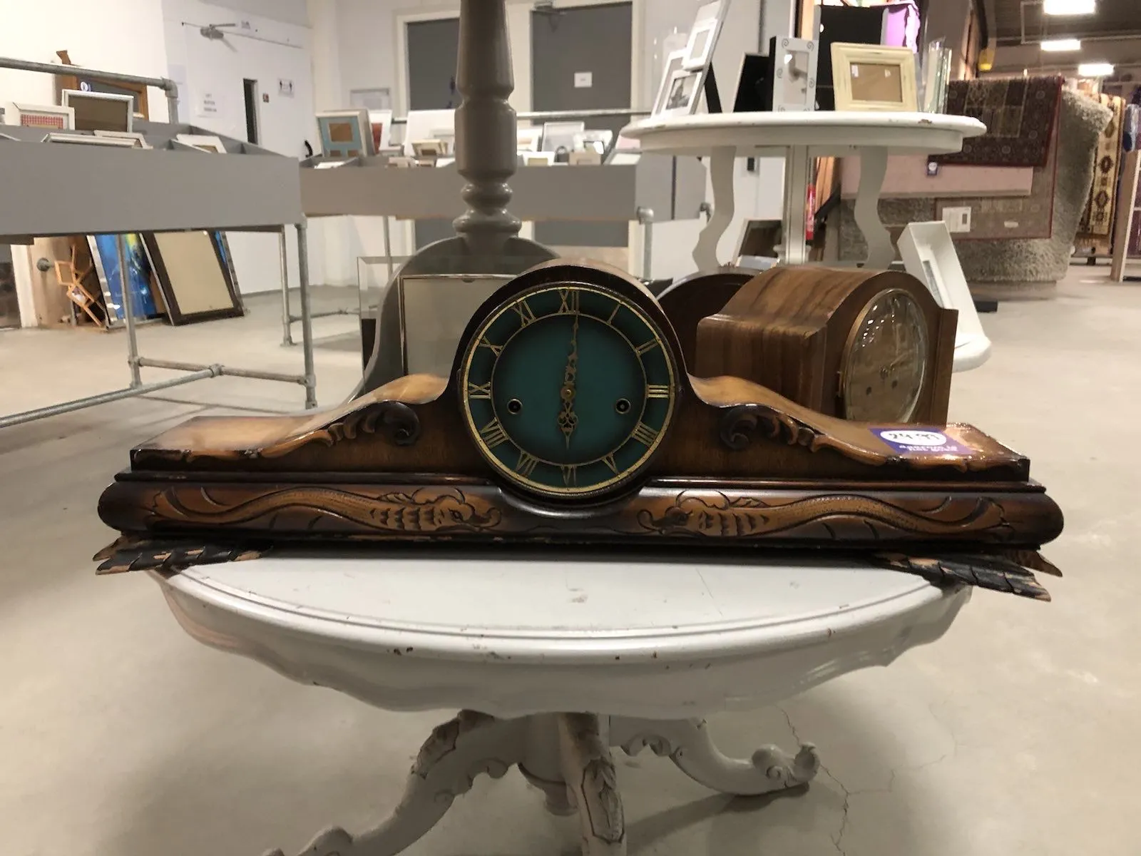 A wide wooden clock with sculpted snakelike creatures points at 1 minute past 6.