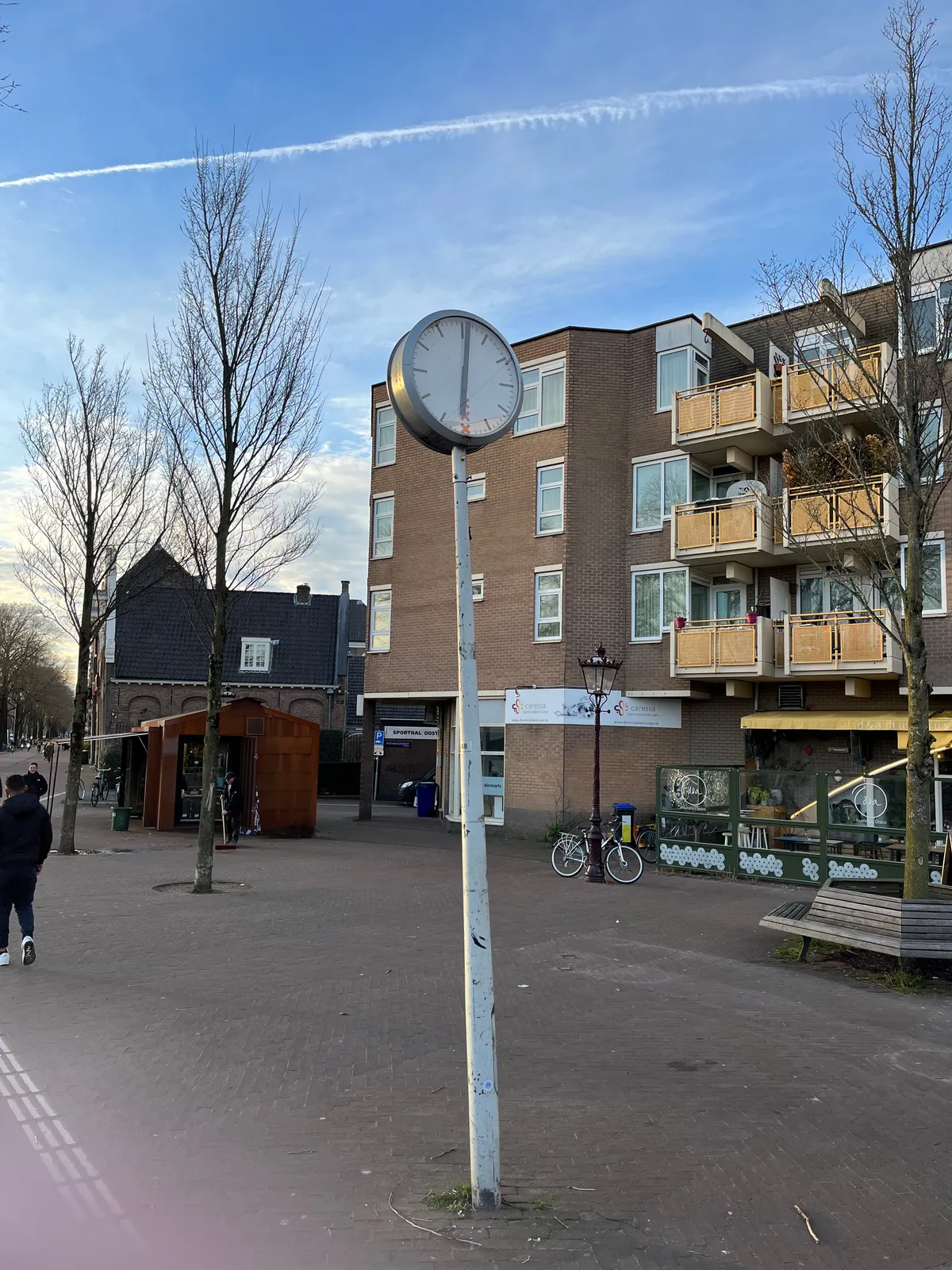 A clock on a pole in Amsterdam points at 1 minute past six.