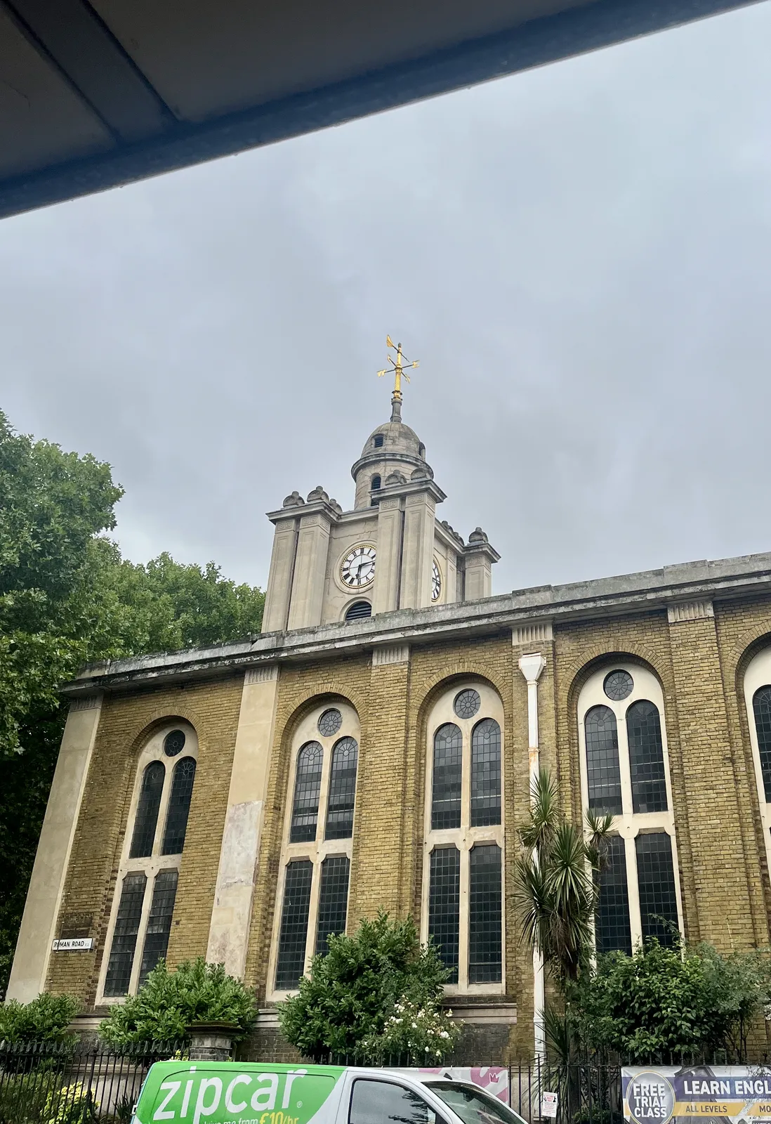 A large, churchlike building, with a tower on it, with a golden crown. On the tower is a clock, which points at 13 minutes past six